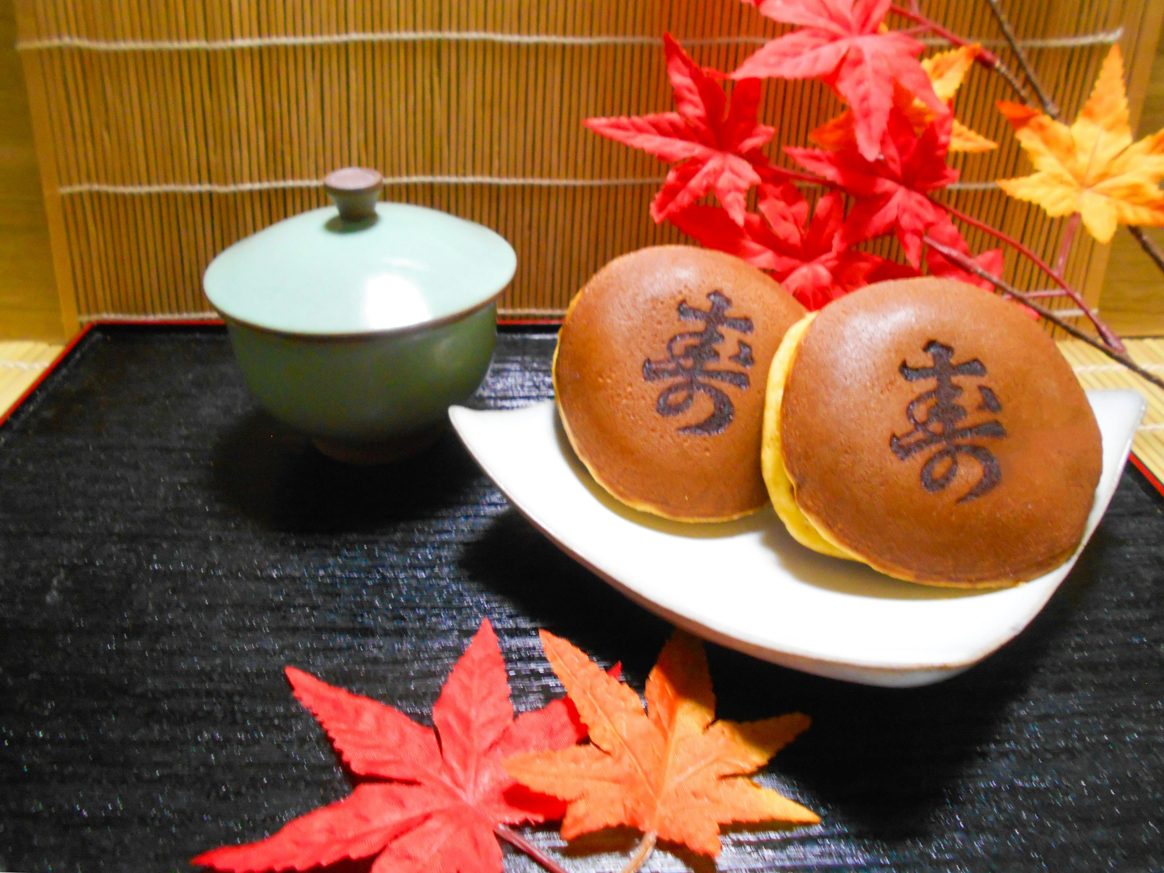 Assiette de douceurs japonaises avec des feuilles d'automne et un bol de thé vert