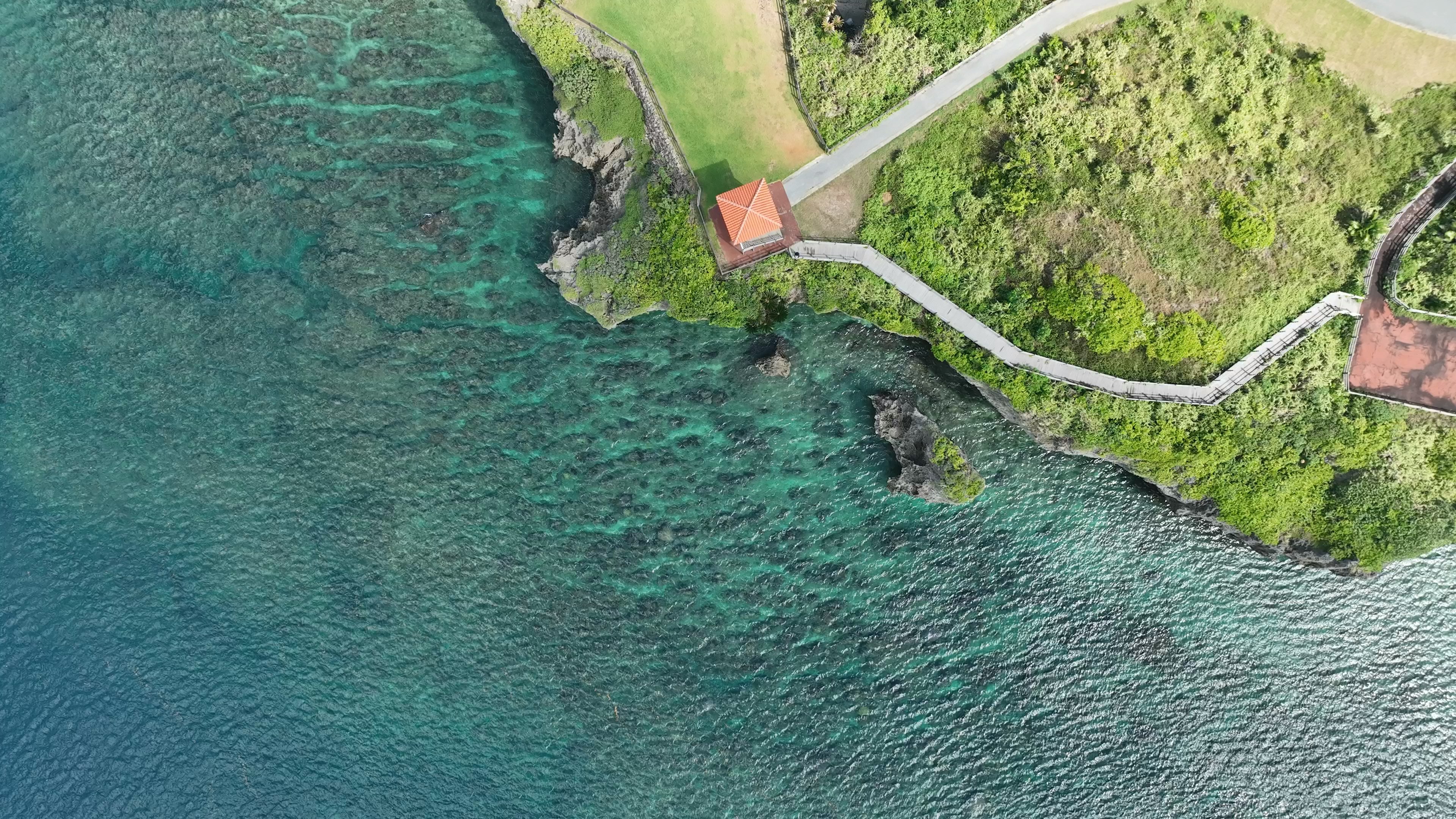 鳥瞰圖顯示青綠色海洋與綠色山丘上的小建築