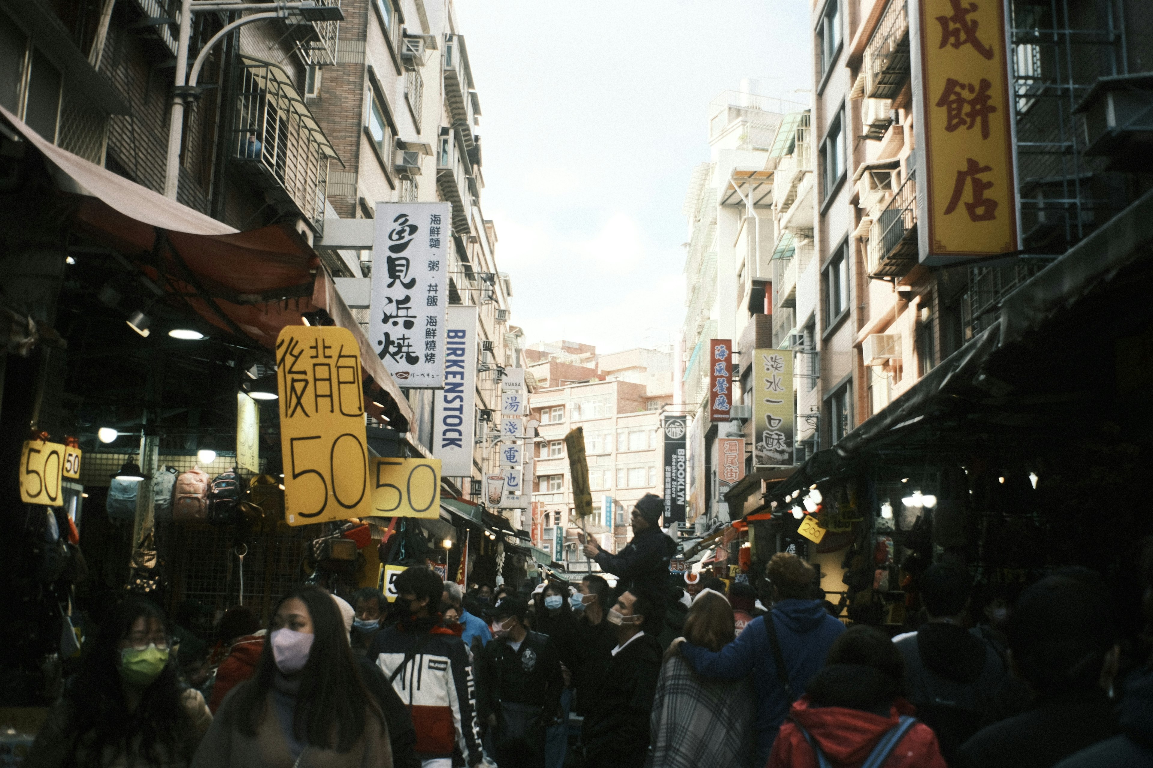 Bustling market street filled with people and colorful signs