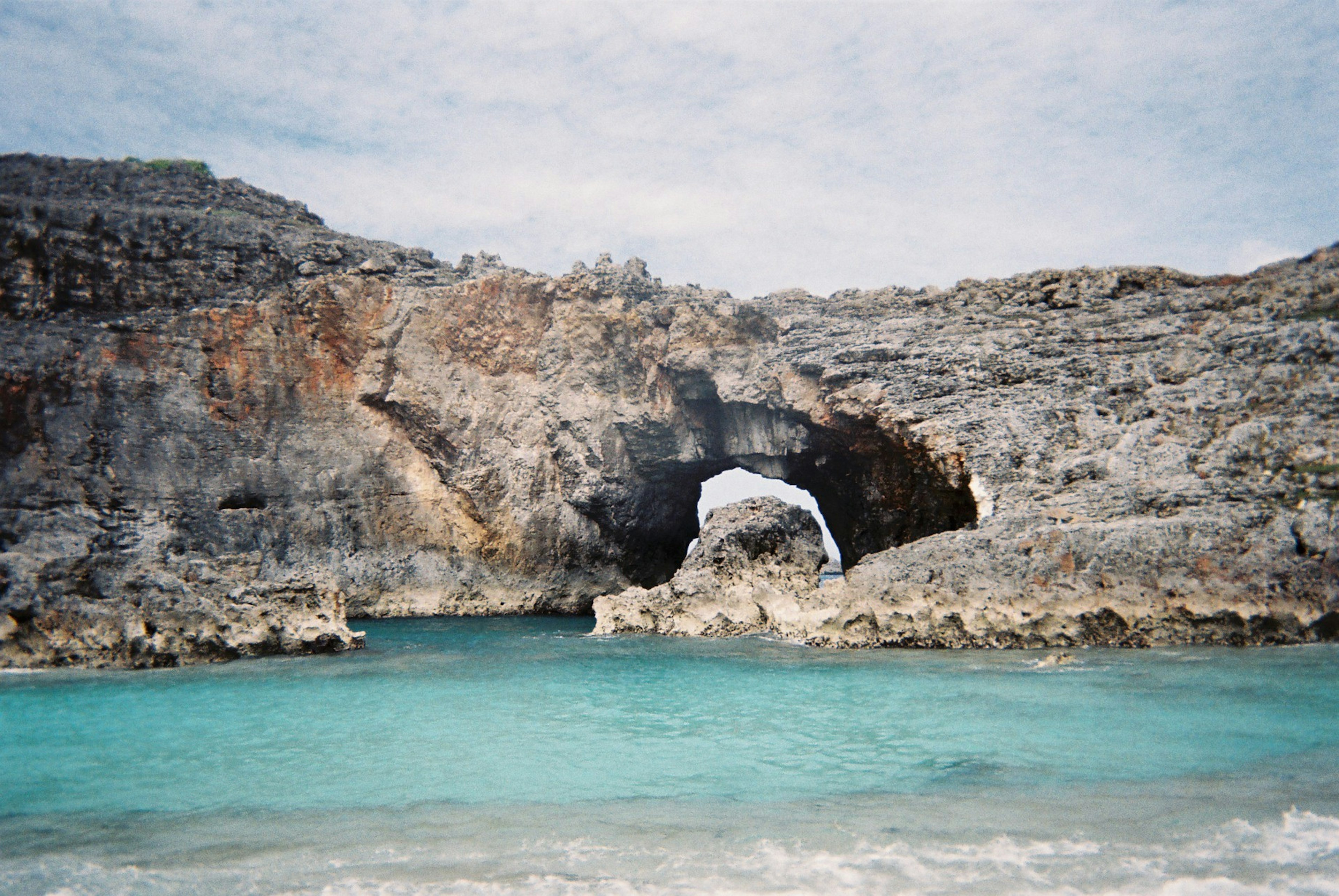 Arco natural entre acantilados rocosos y agua turquesa