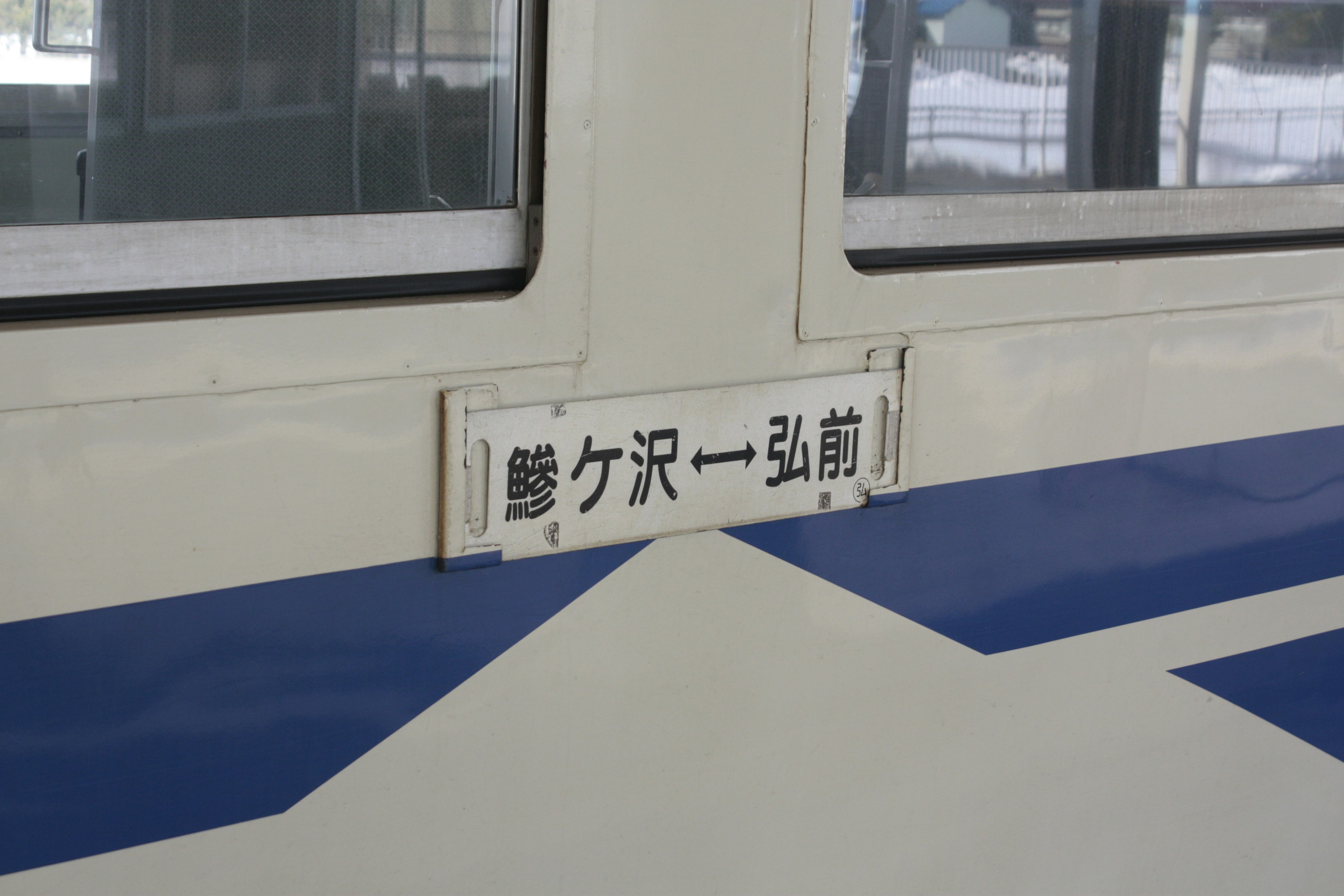 Ventana de tren con placa de nombre de estación y franja azul