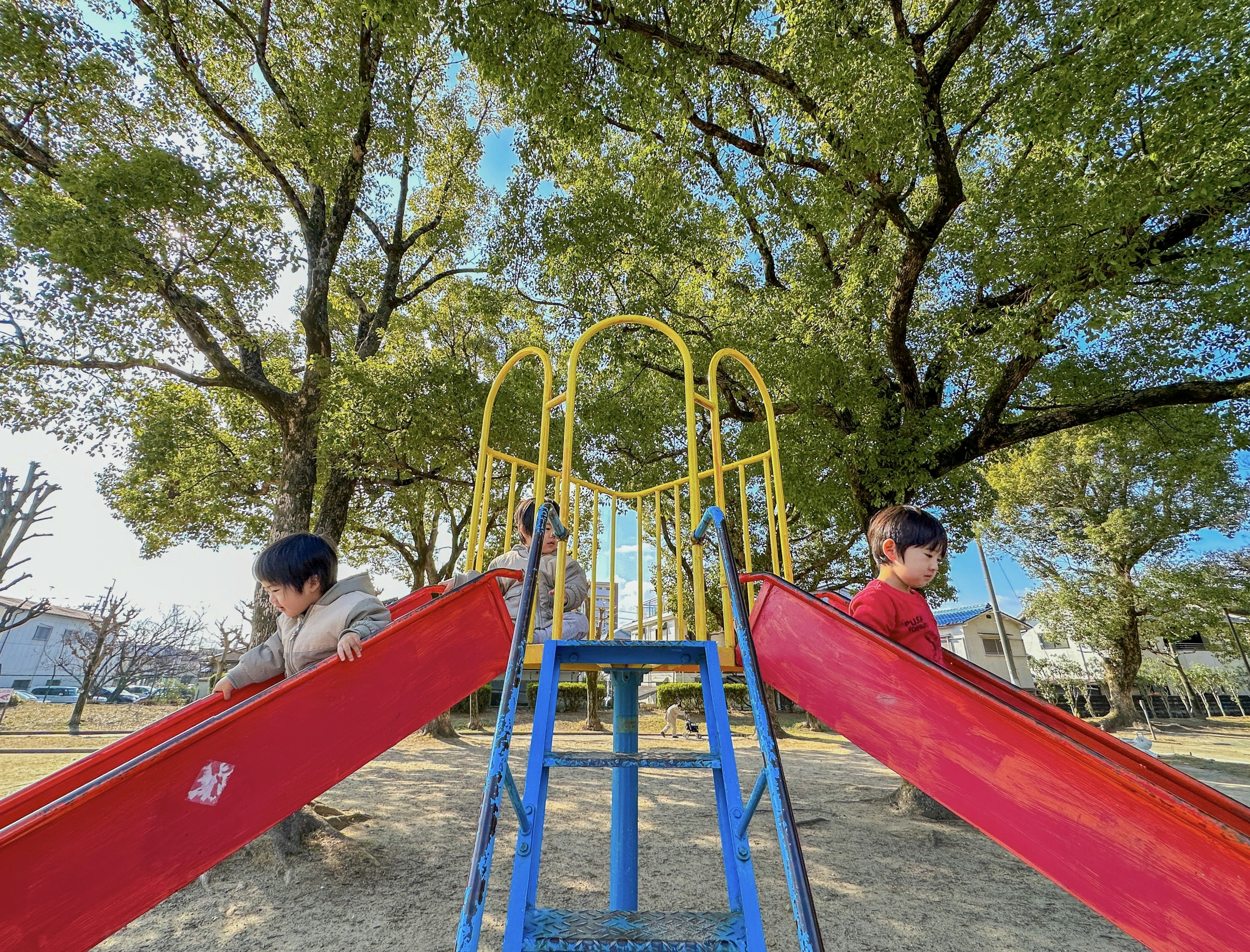 Two children playing on slides in a park