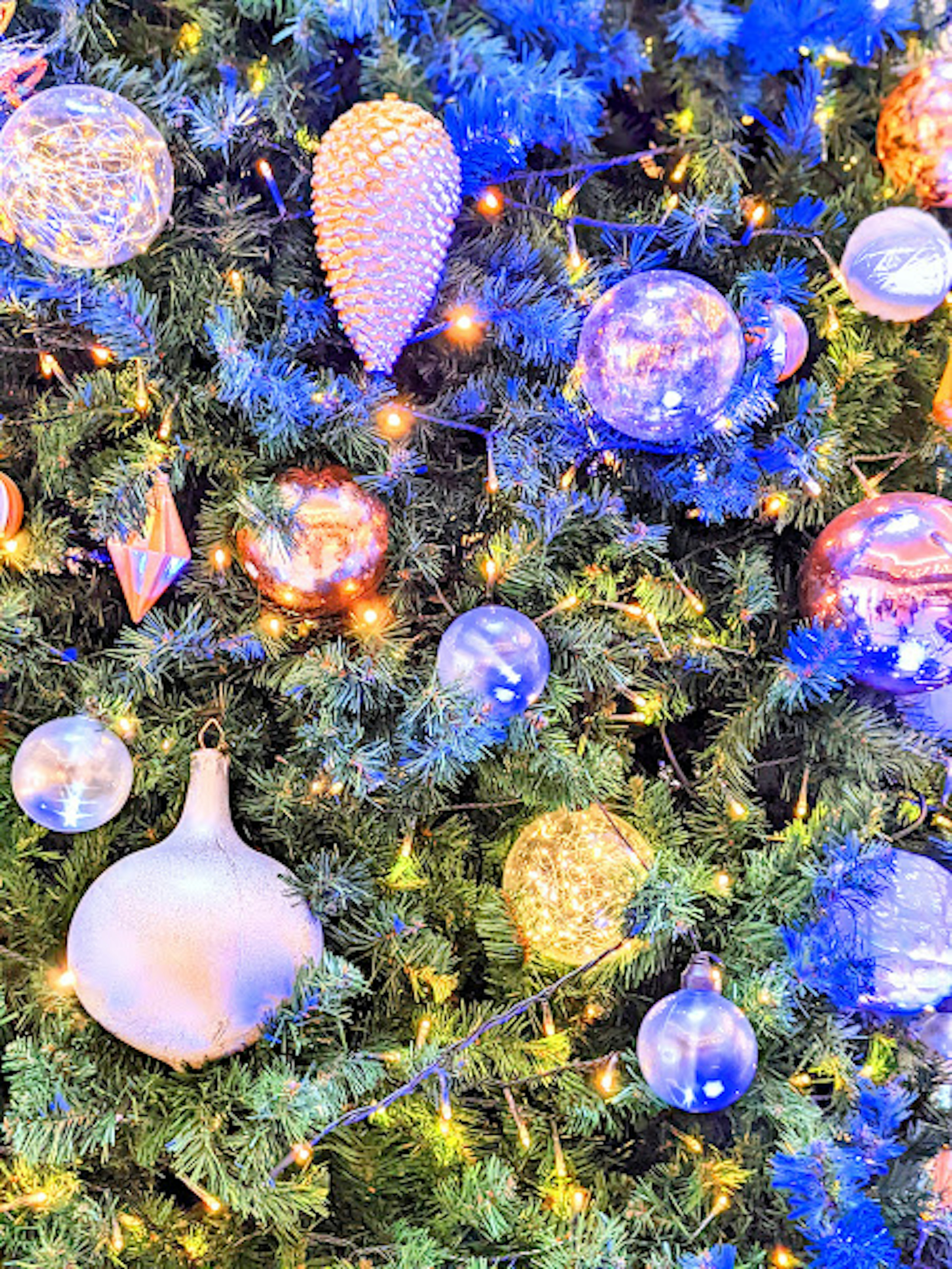 Decorative ornaments on a Christmas tree illuminated by blue lights