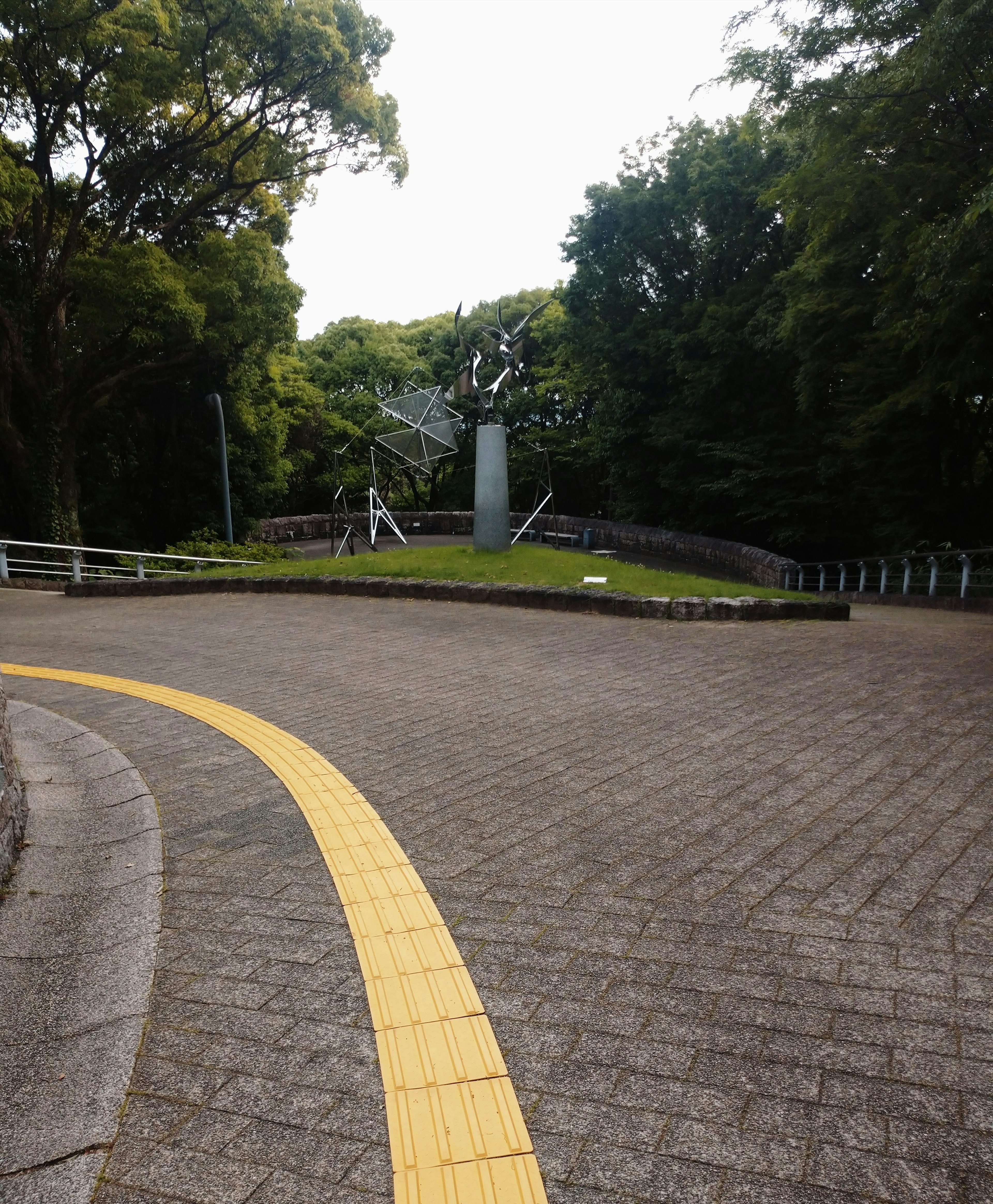 Unique sculpture in a green park pathway with a yellow line