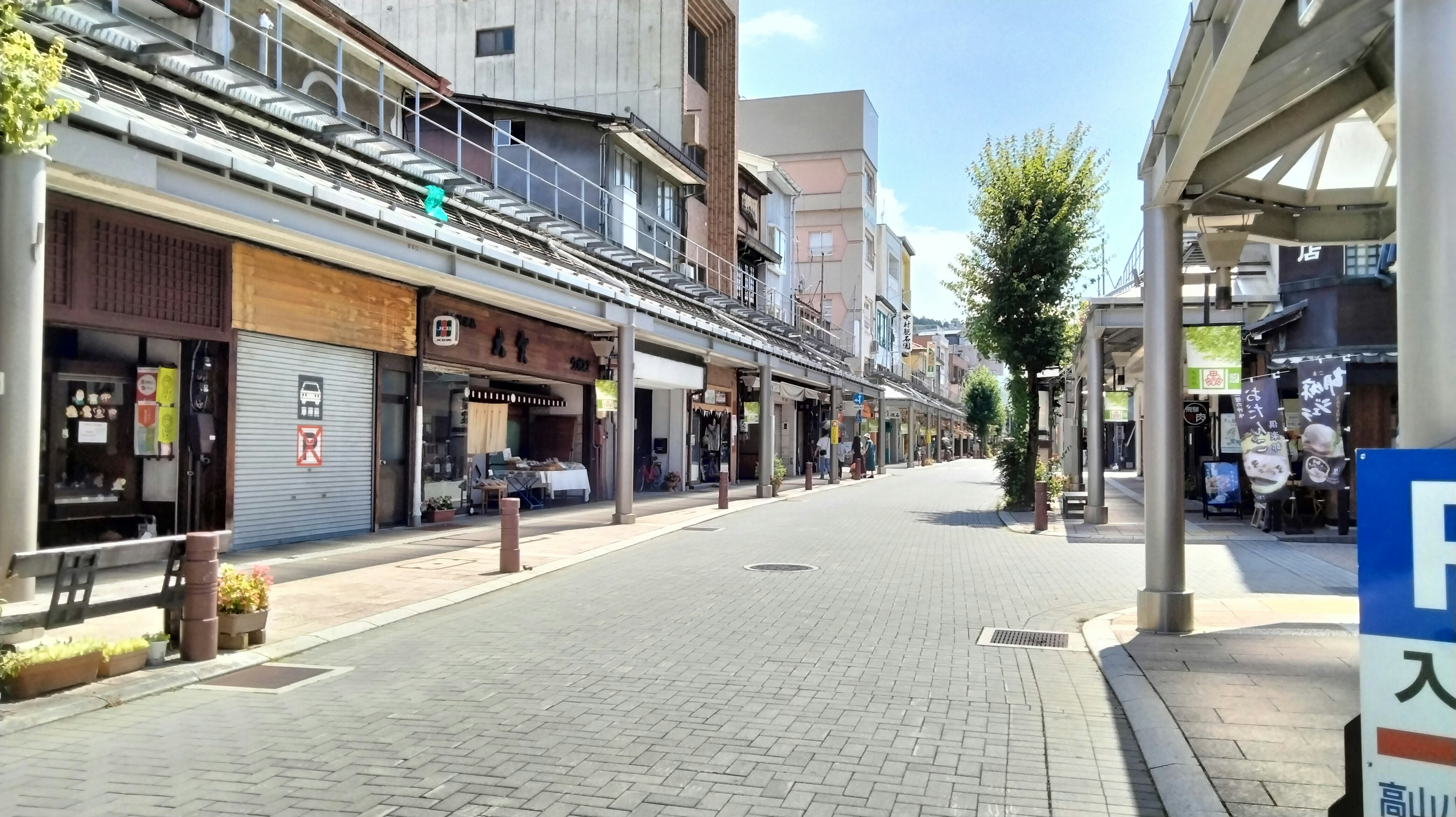 Quiet street lined with shops and green trees