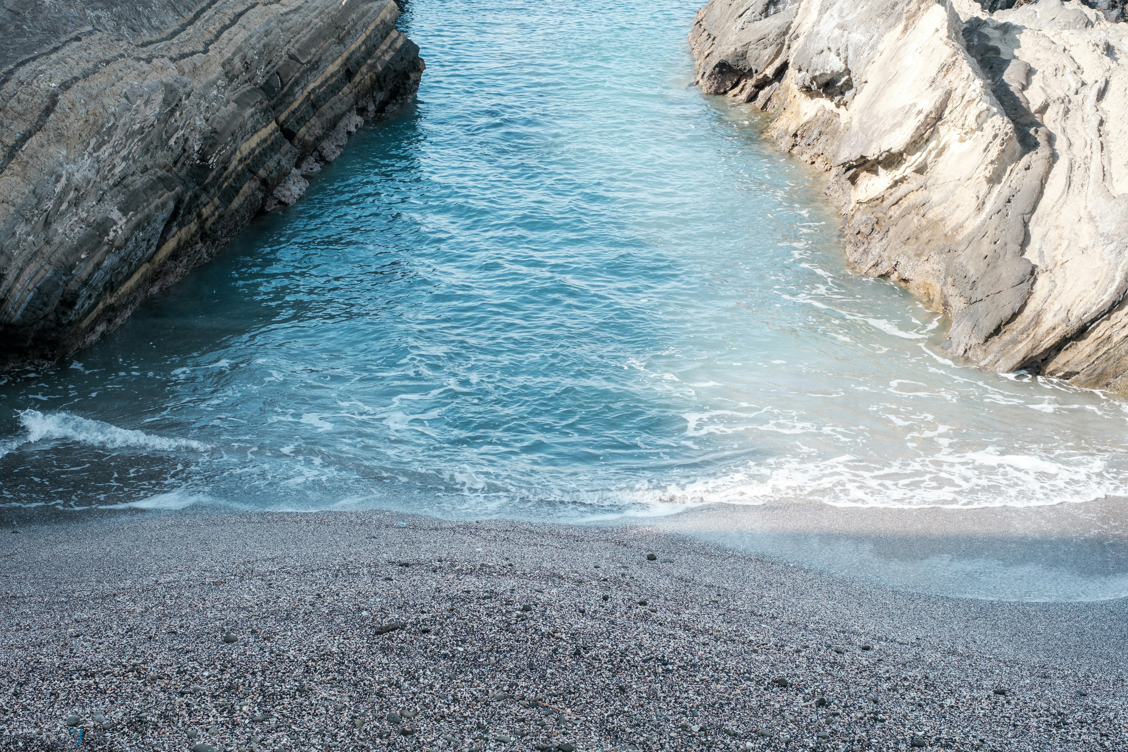 Vista escénica de una playa de arena entre acantilados rocosos y agua azul clara