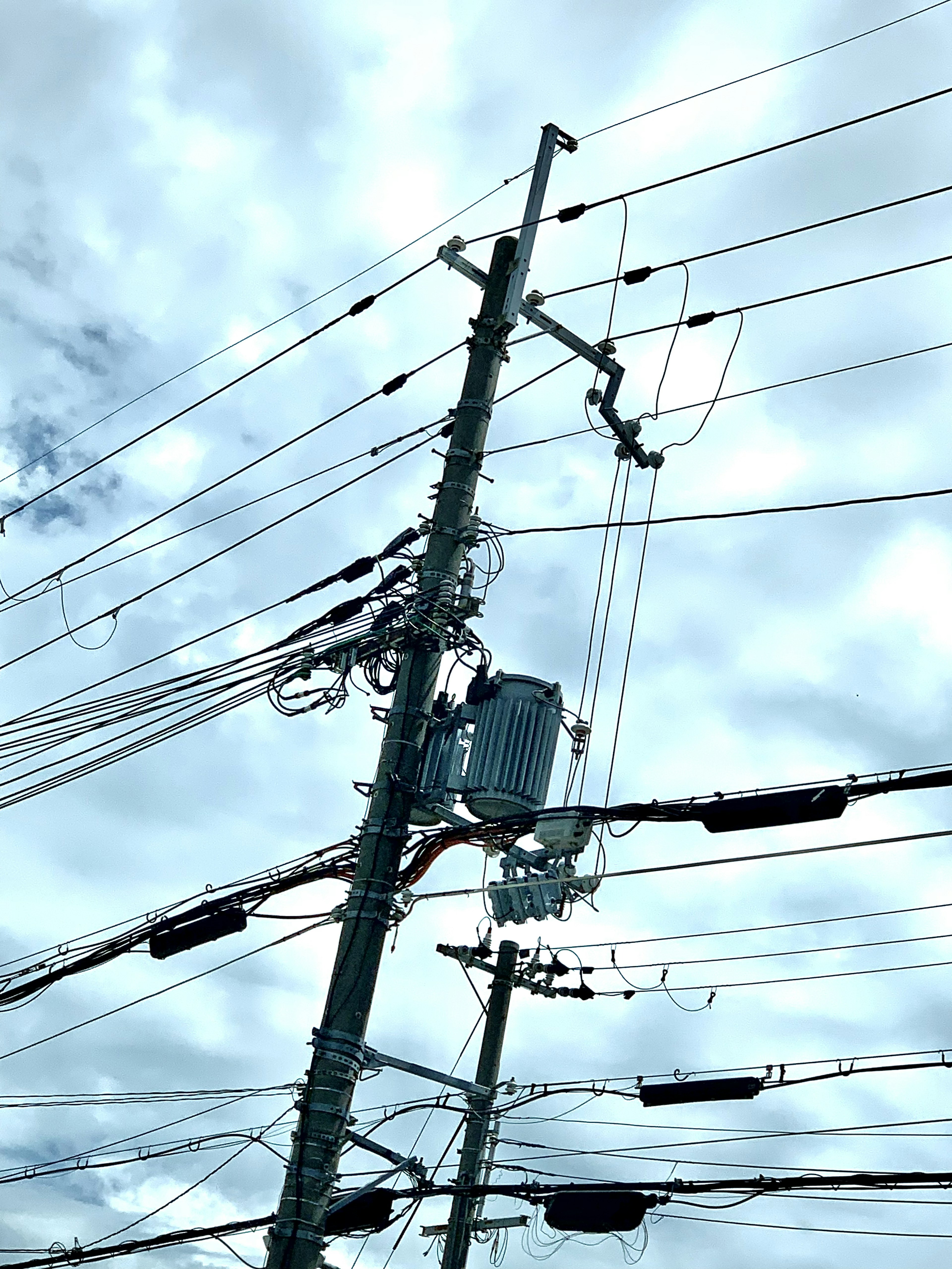 Power pole with intersecting wires under a cloudy sky