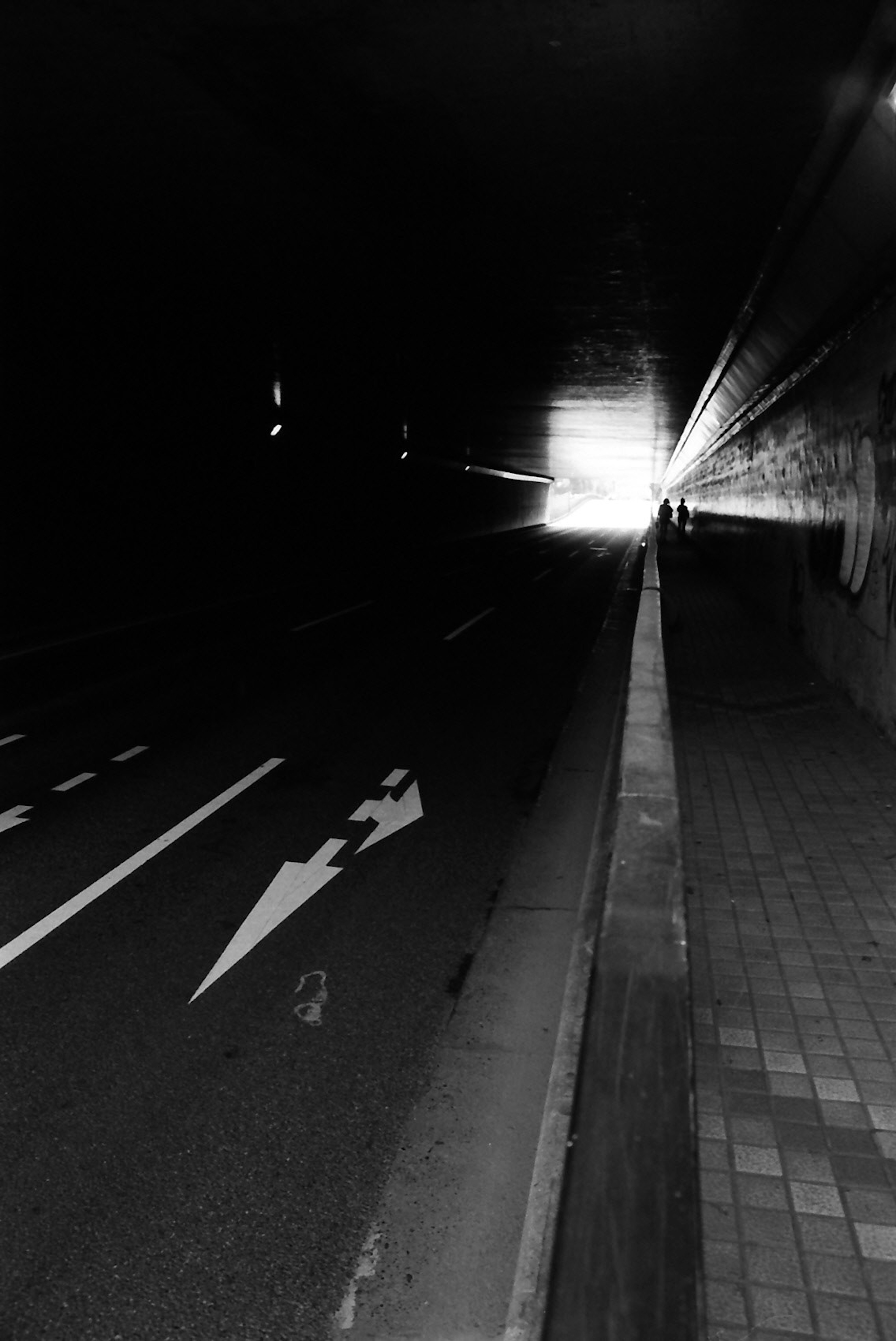 Dark tunnel with a bright exit and road markings