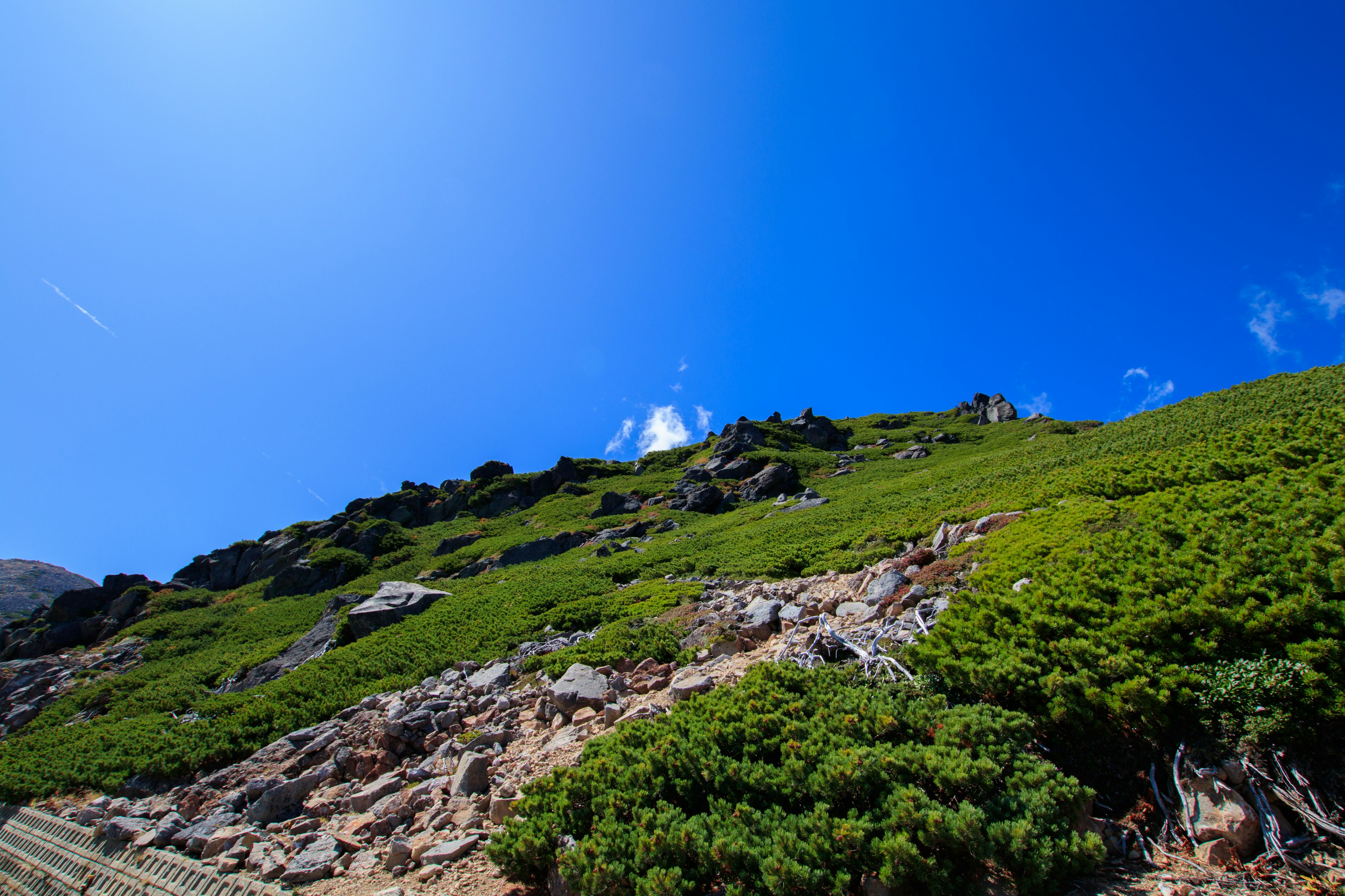 Vista panoramica di collina verde e terreno roccioso sotto un cielo azzurro