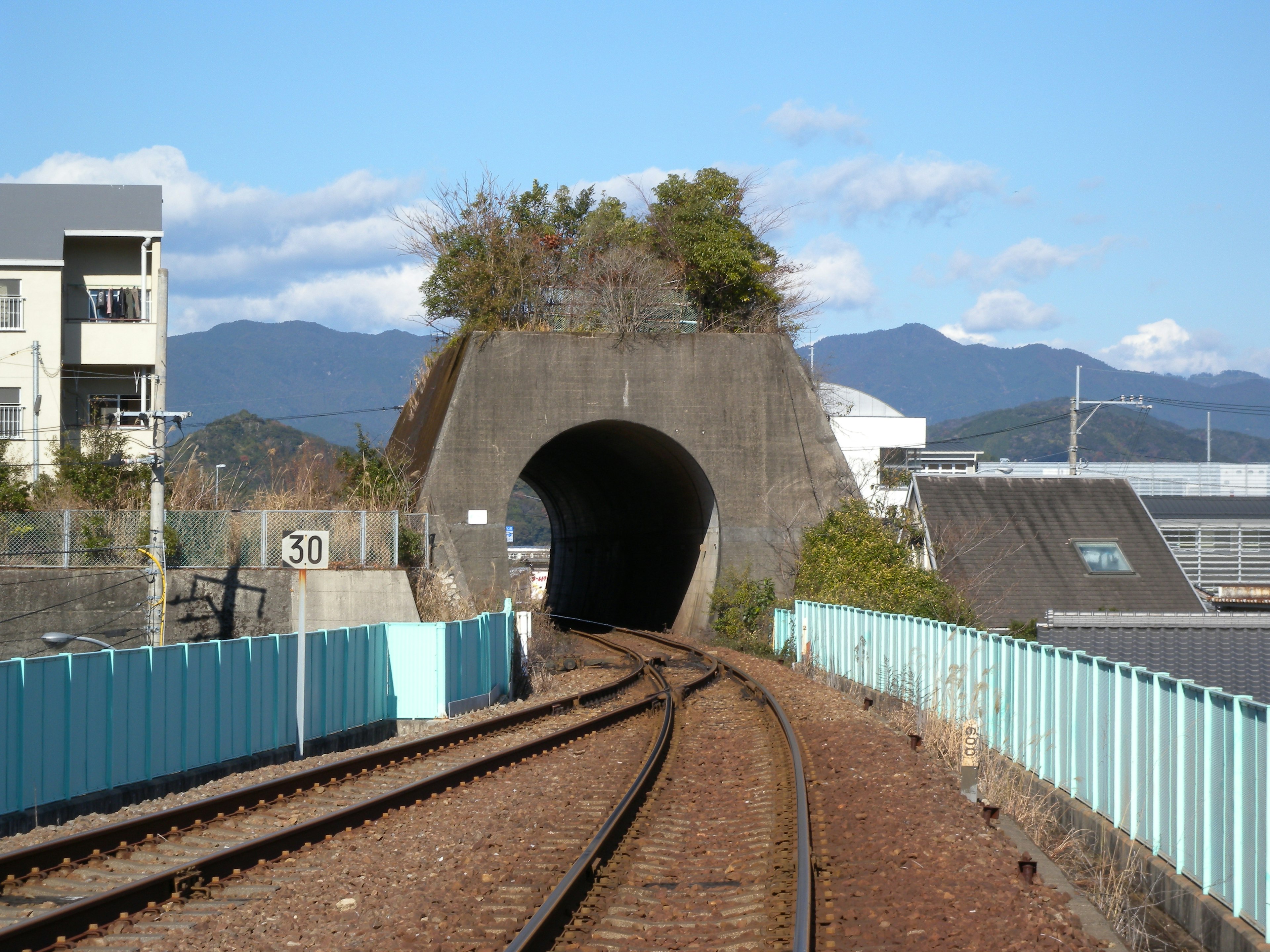 Landschaft mit Bahngleisen und einem Tunnel Grün auf dem Tunnel Japanische Landschaft