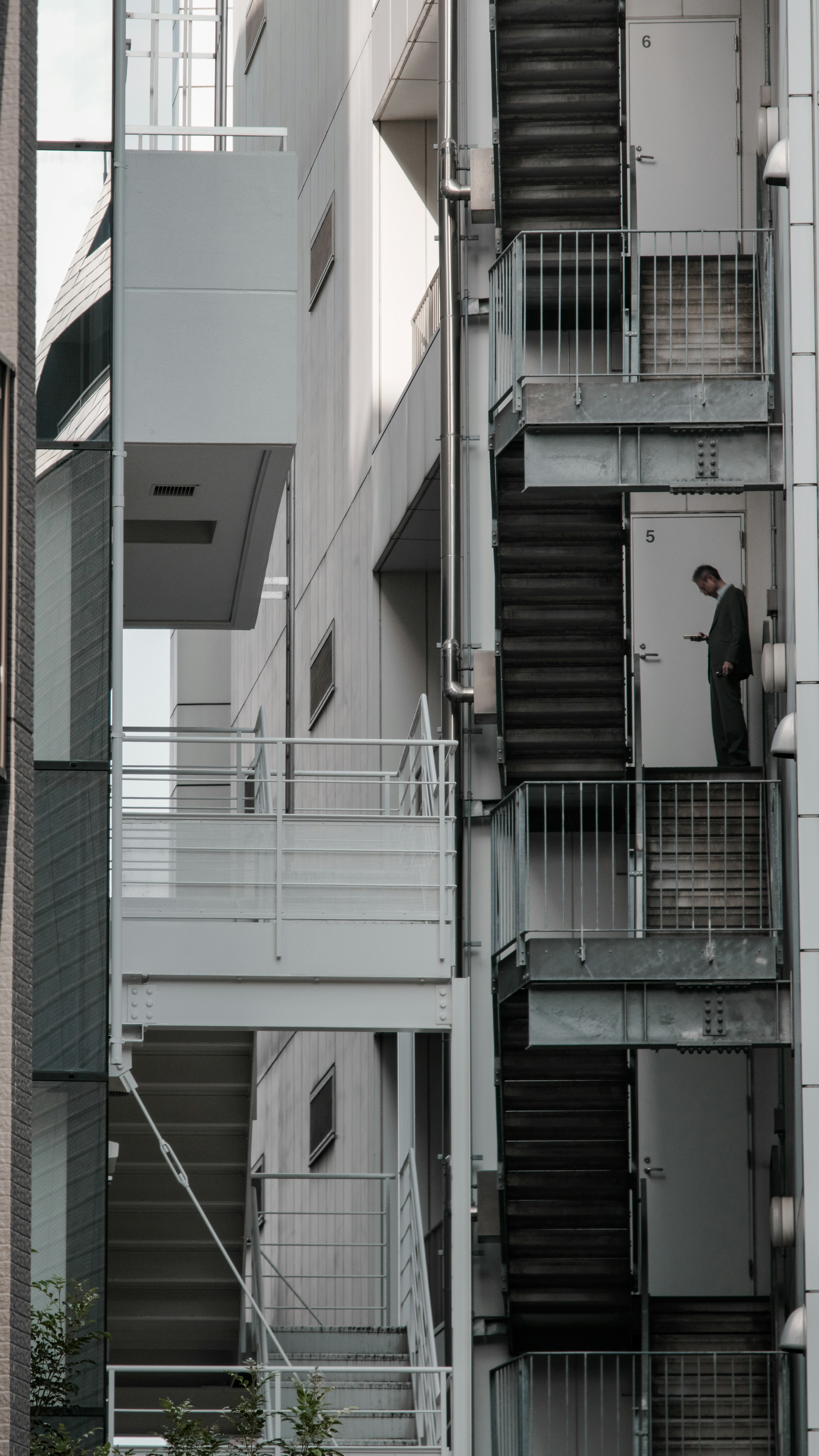 Un uomo in piedi vicino a una scala esterna di un edificio appartamento stretto