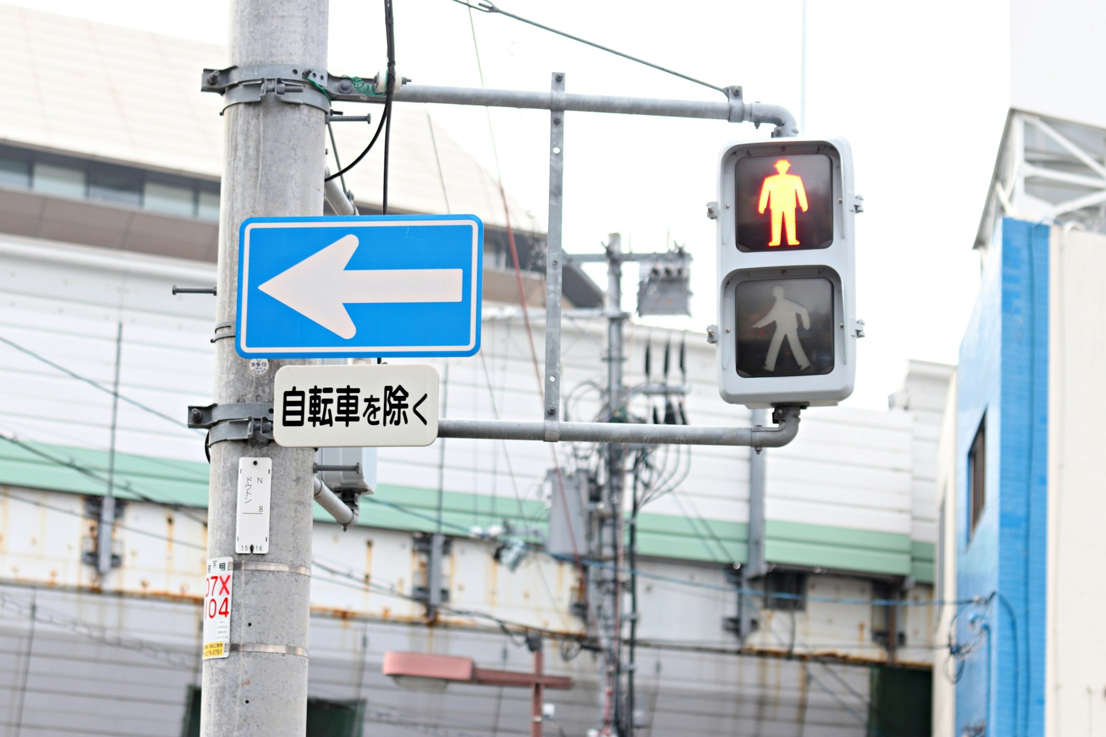 Street corner featuring a blue left arrow sign and a pedestrian signal