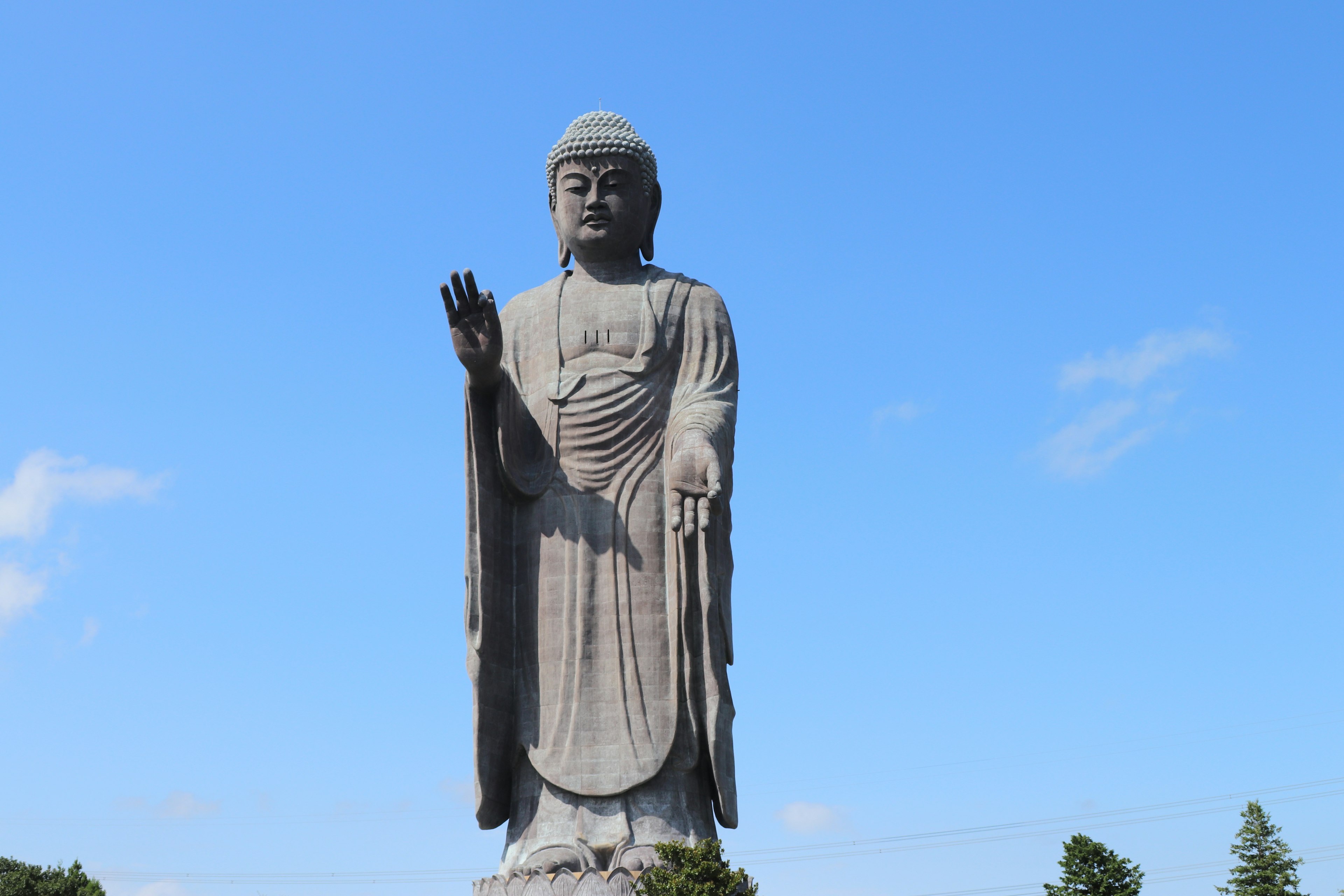 A large statue of Buddha standing against a blue sky