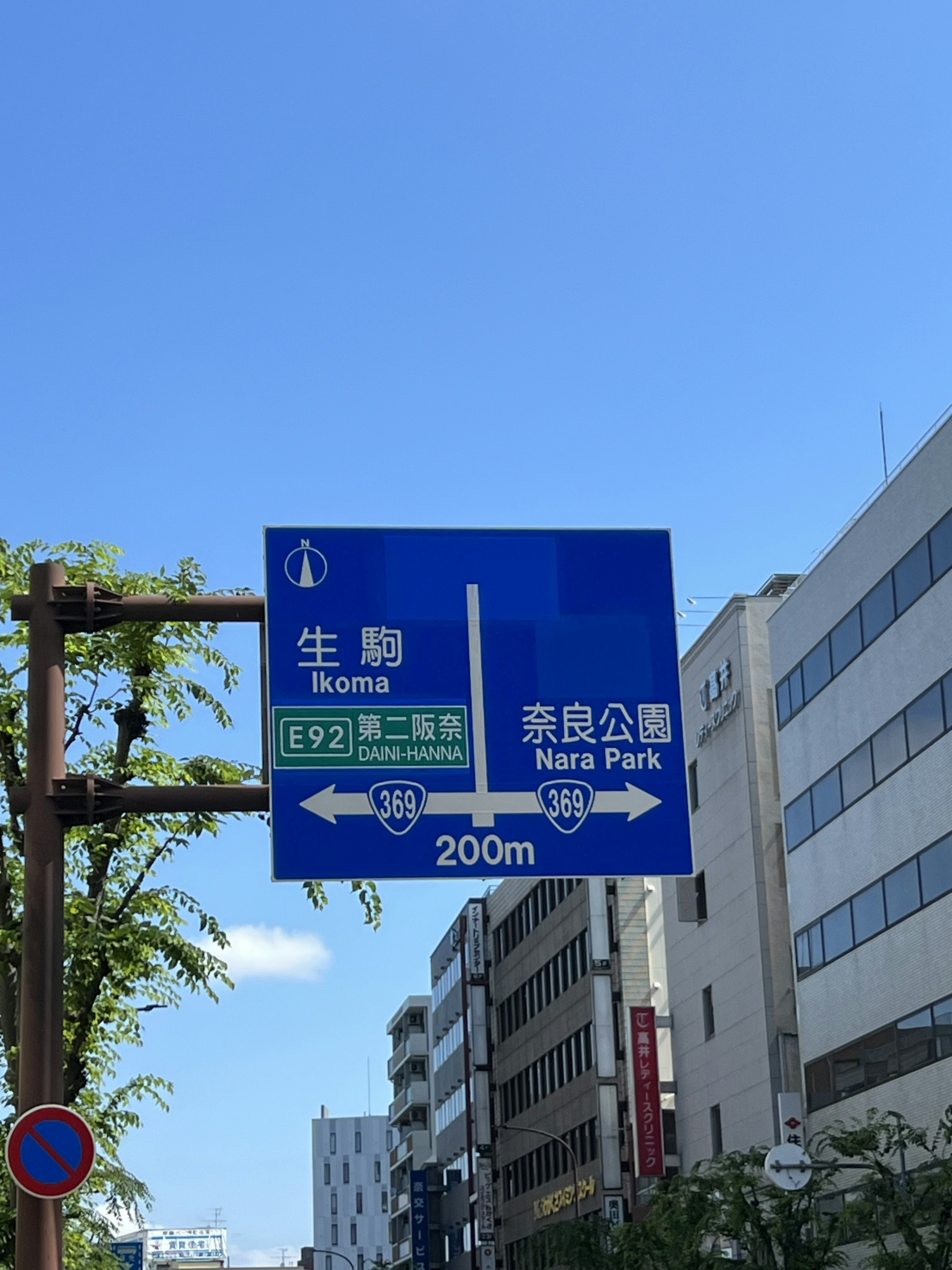 Blue road sign indicating directions to Ikuta and Shinjuku Park