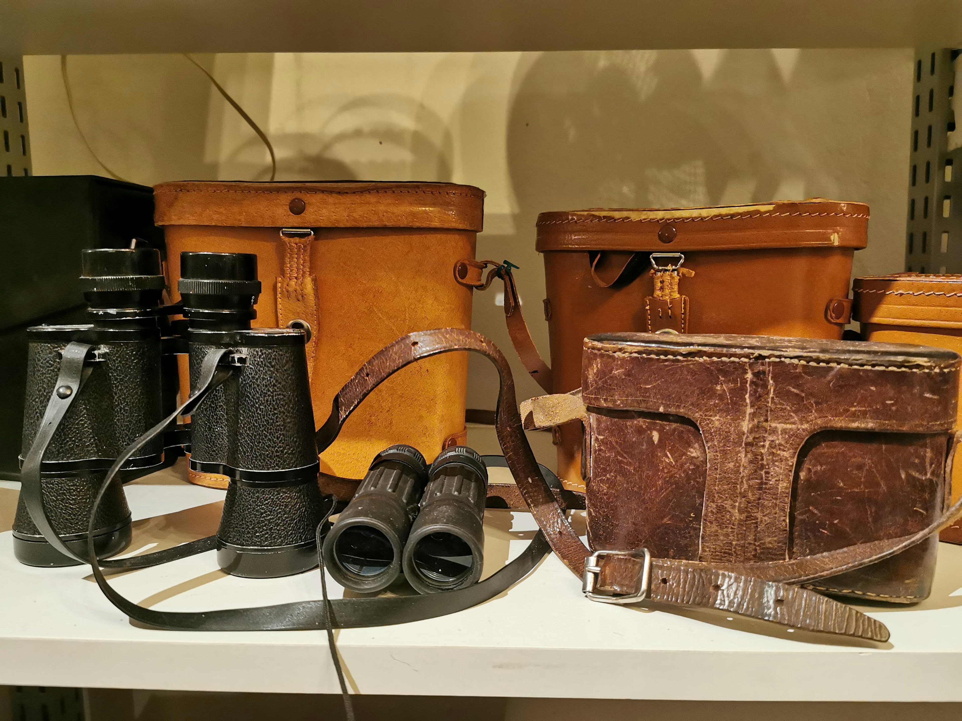 Set of binoculars next to wooden boxes and a leather bag