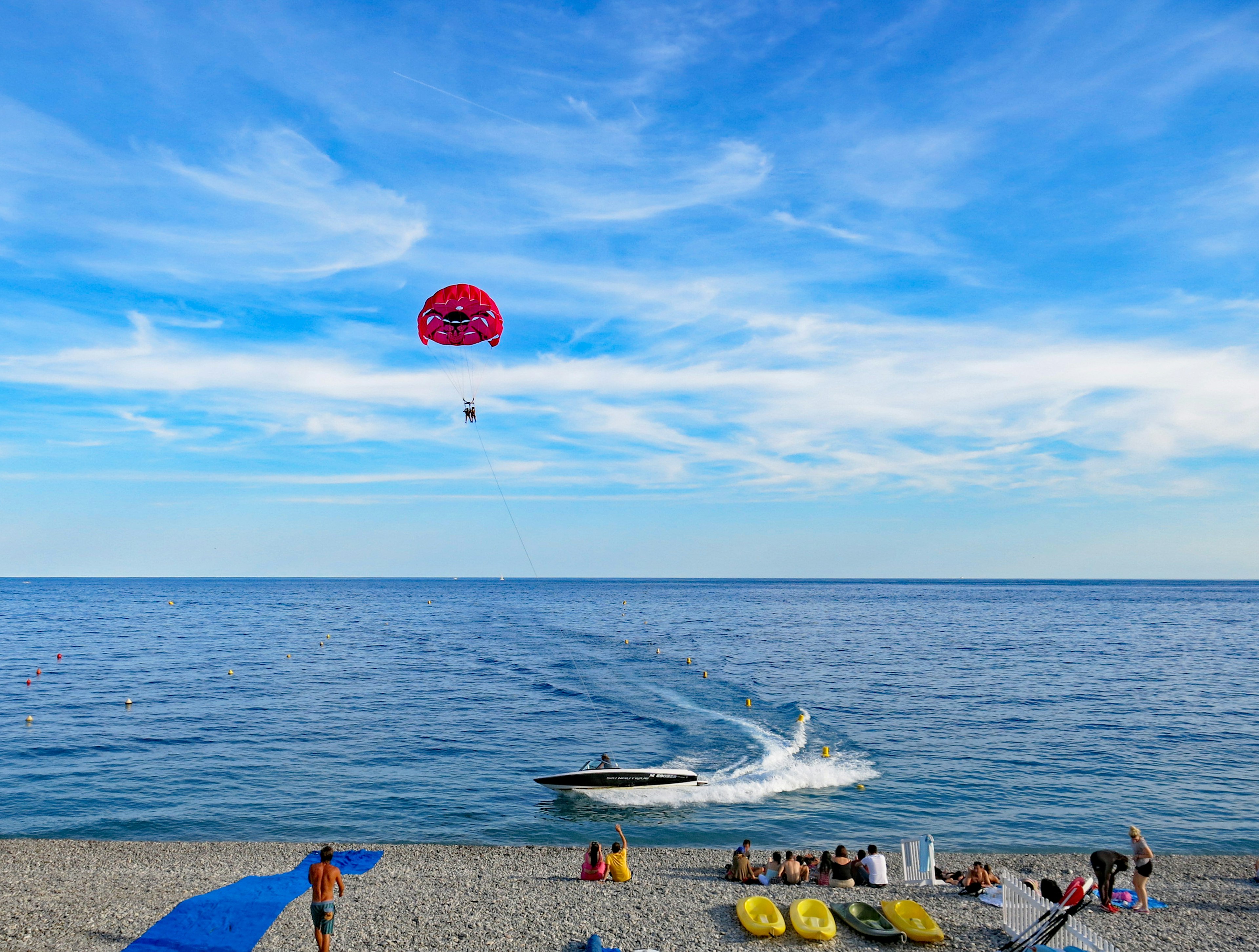 Scena di spiaggia con parapendio e barca sotto un cielo blu