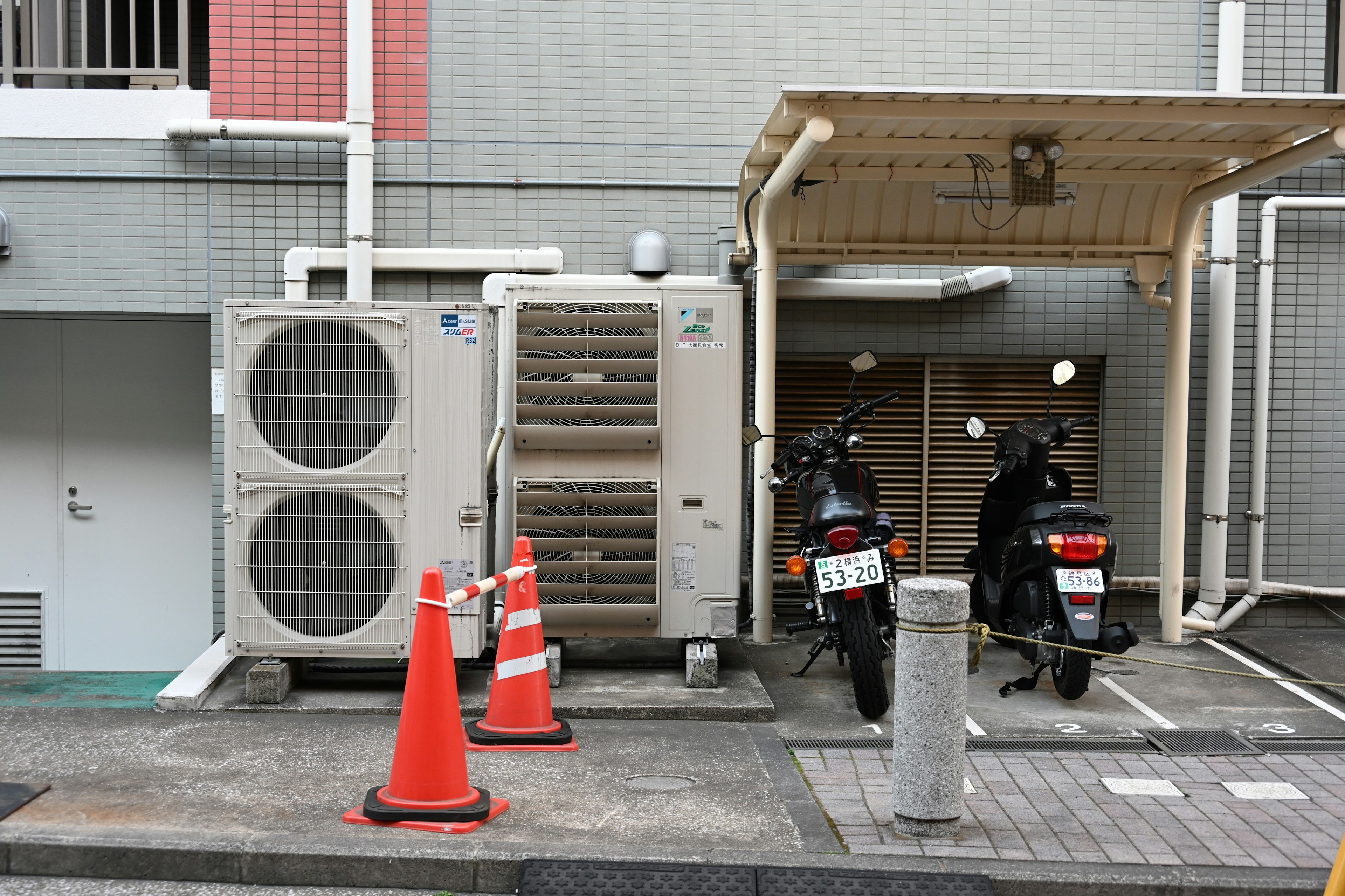 帶有空調單元和兩輛停放摩托車的場景停車區排列著橙色錐