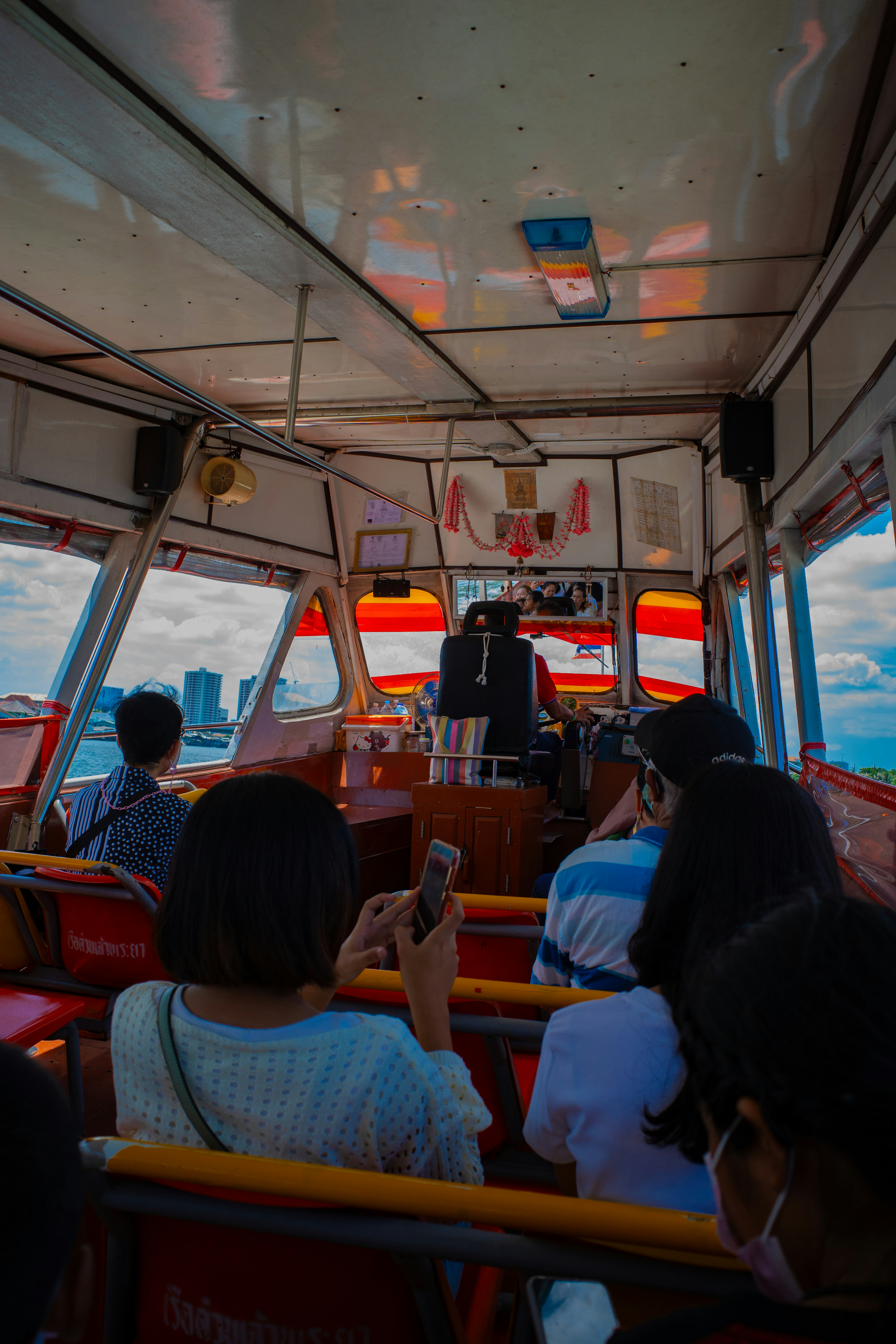 Interior de un barco con pasajeros sentados y un capitán al frente