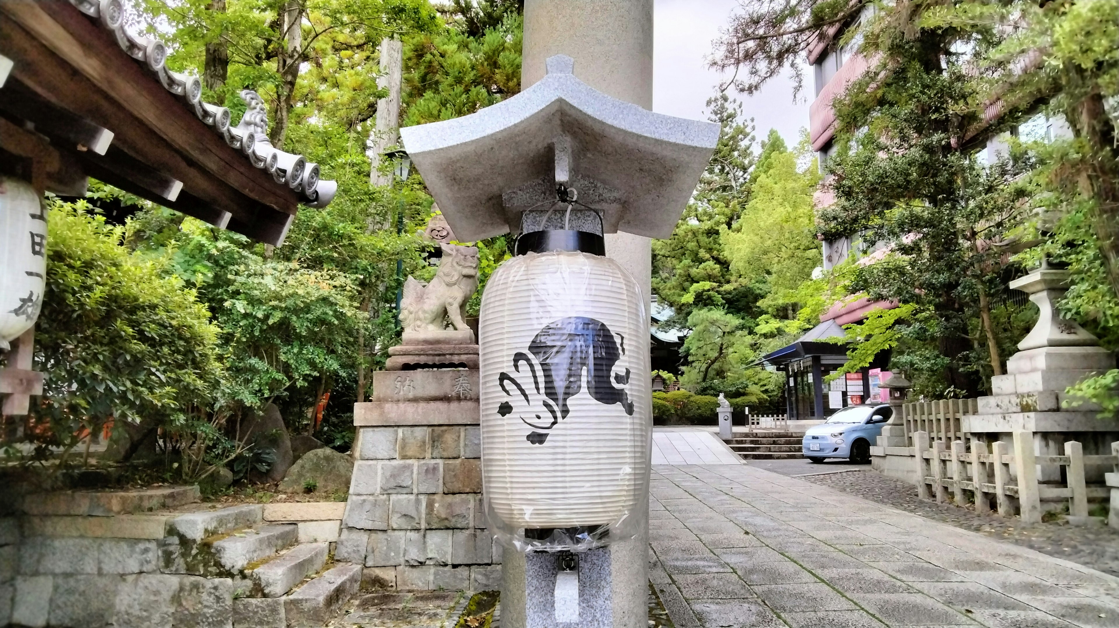 Lantern en pierre sur un chemin de temple avec une illustration de vache entourée d'arbres verts