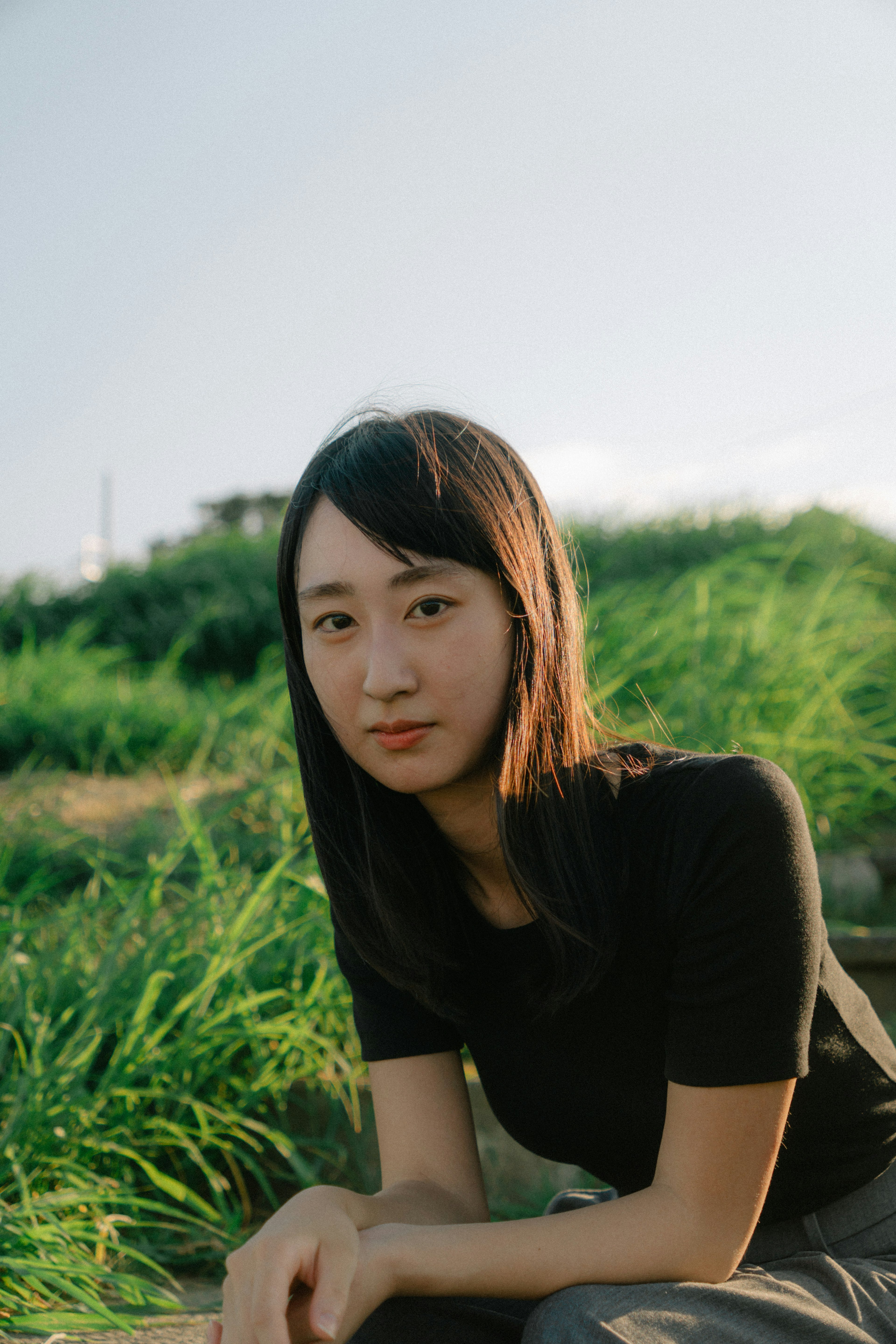 Portrait of a woman sitting in front of a green grass field