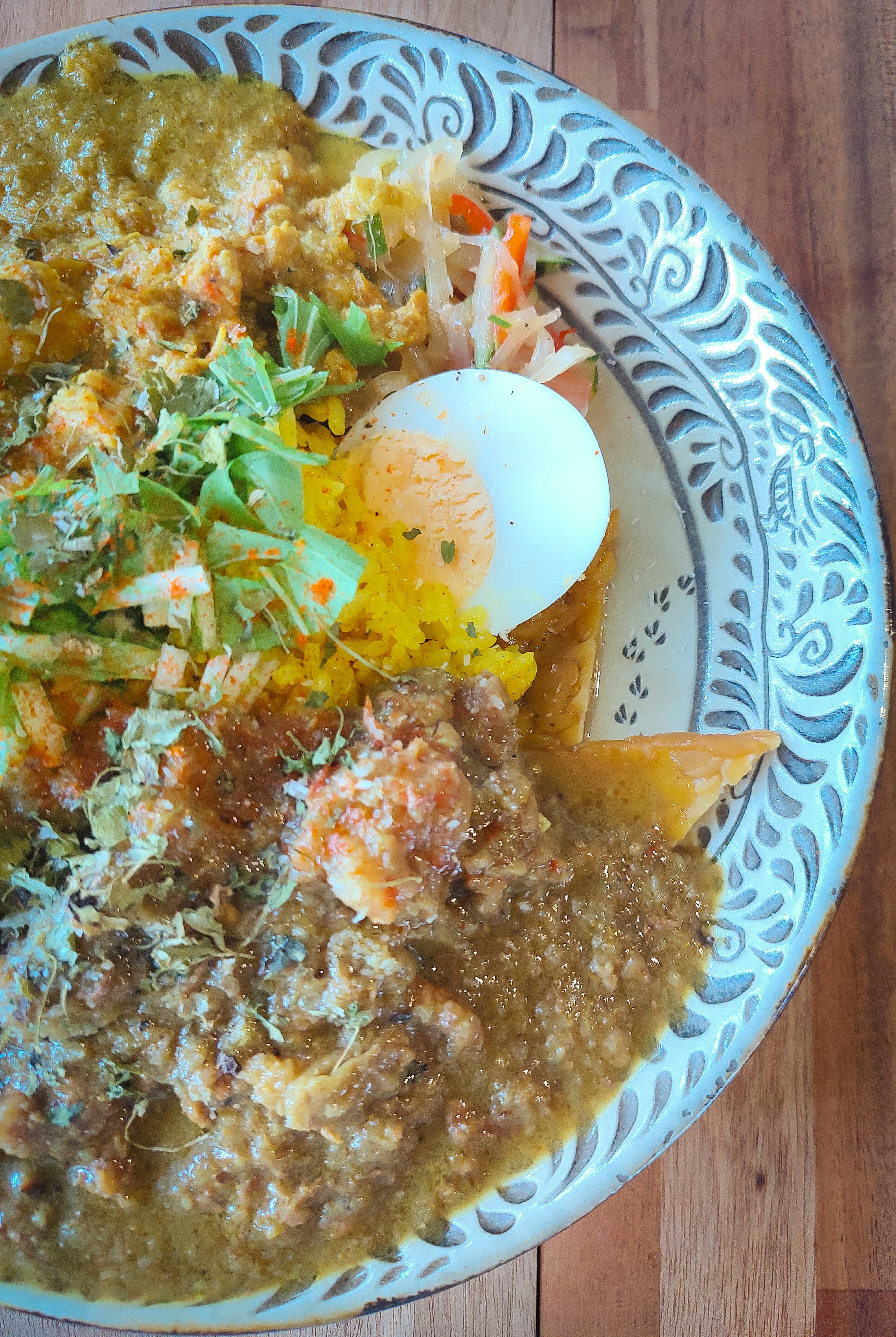 Plate of Indian cuisine featuring rice, curry, salad, and a soft-boiled egg