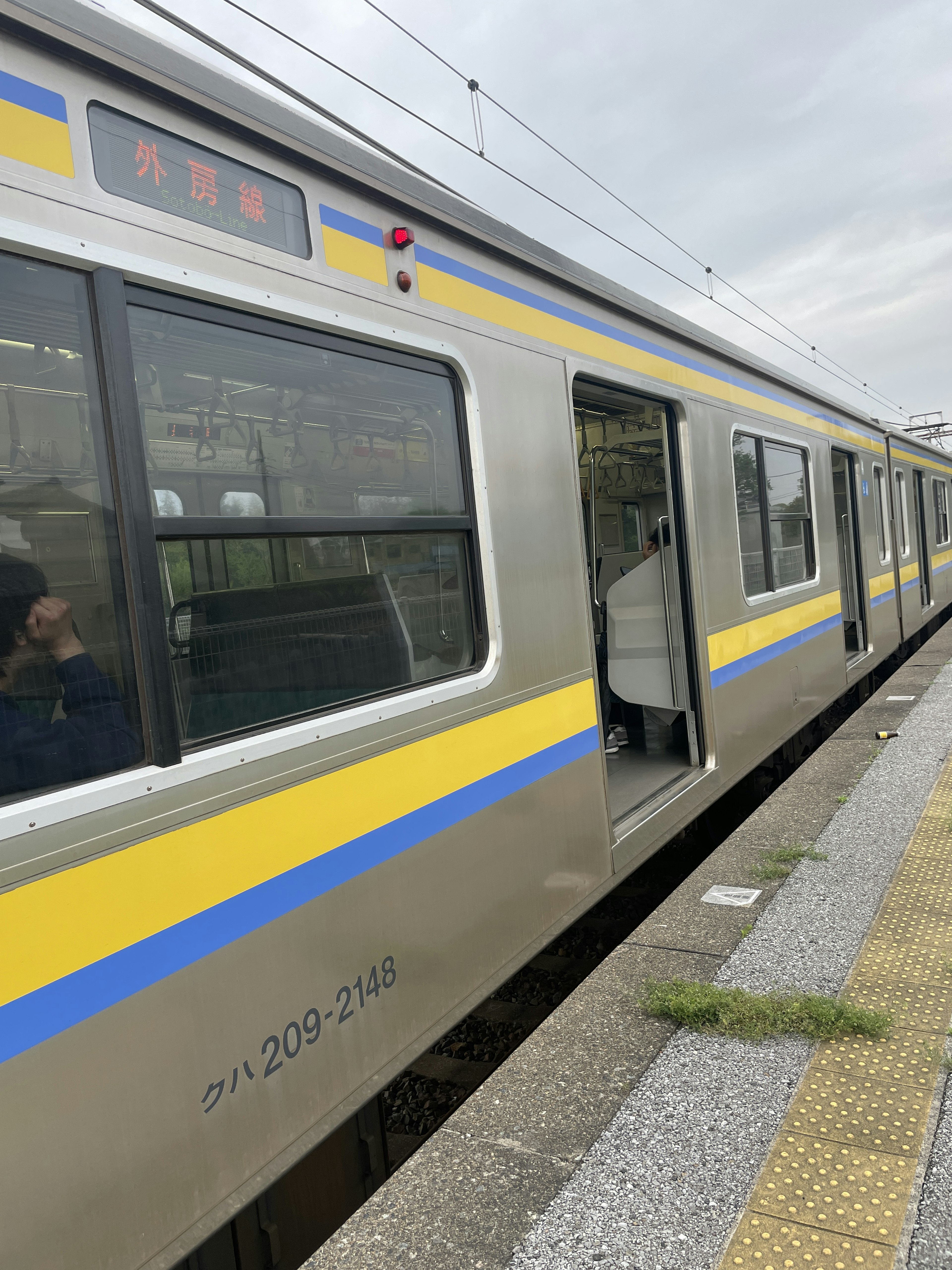 黄色と青のストライプのある銀色の電車が駅で停車している