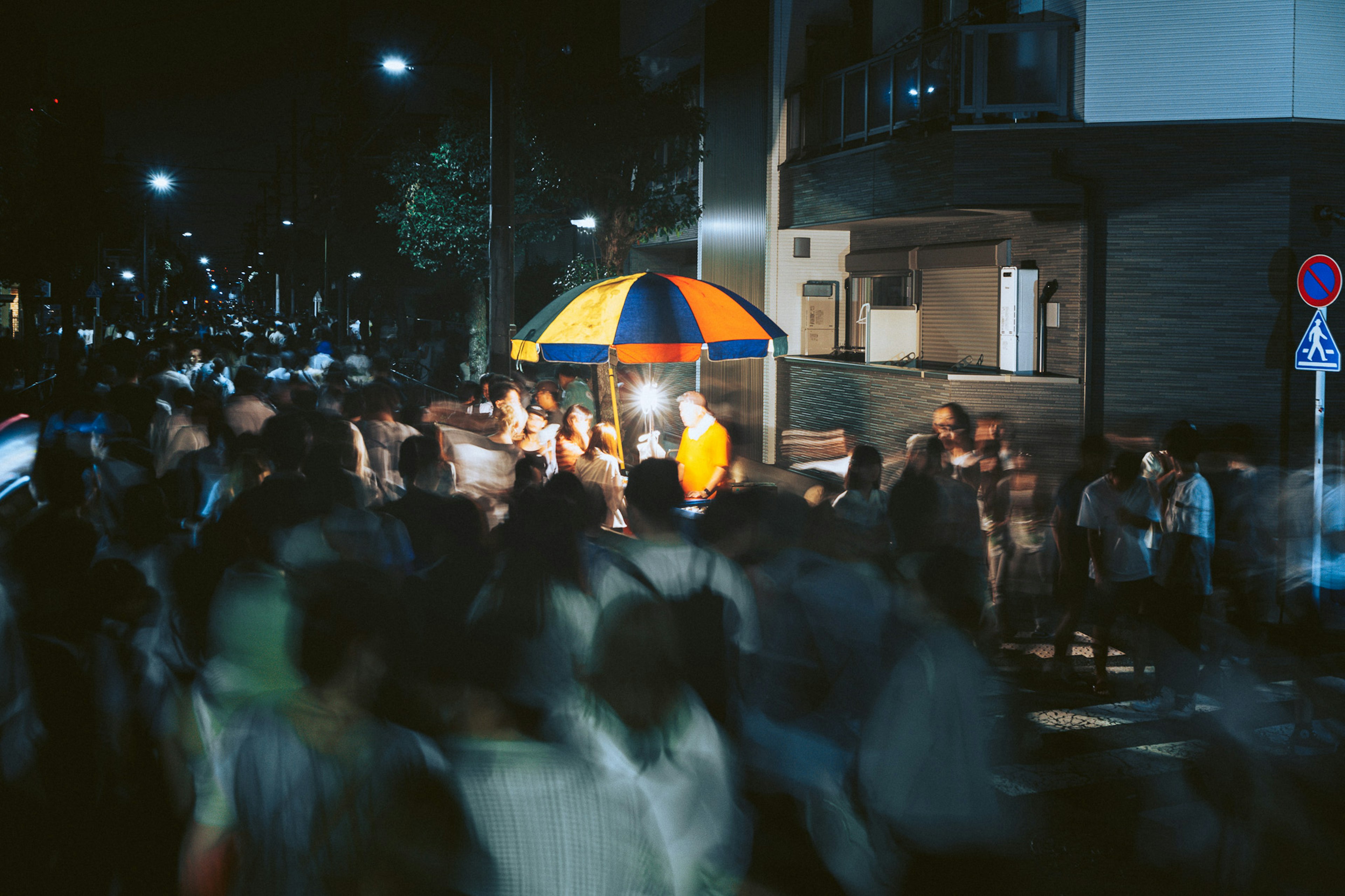 Foule de personnes dans une rue animée la nuit avec un stand de nourriture coloré