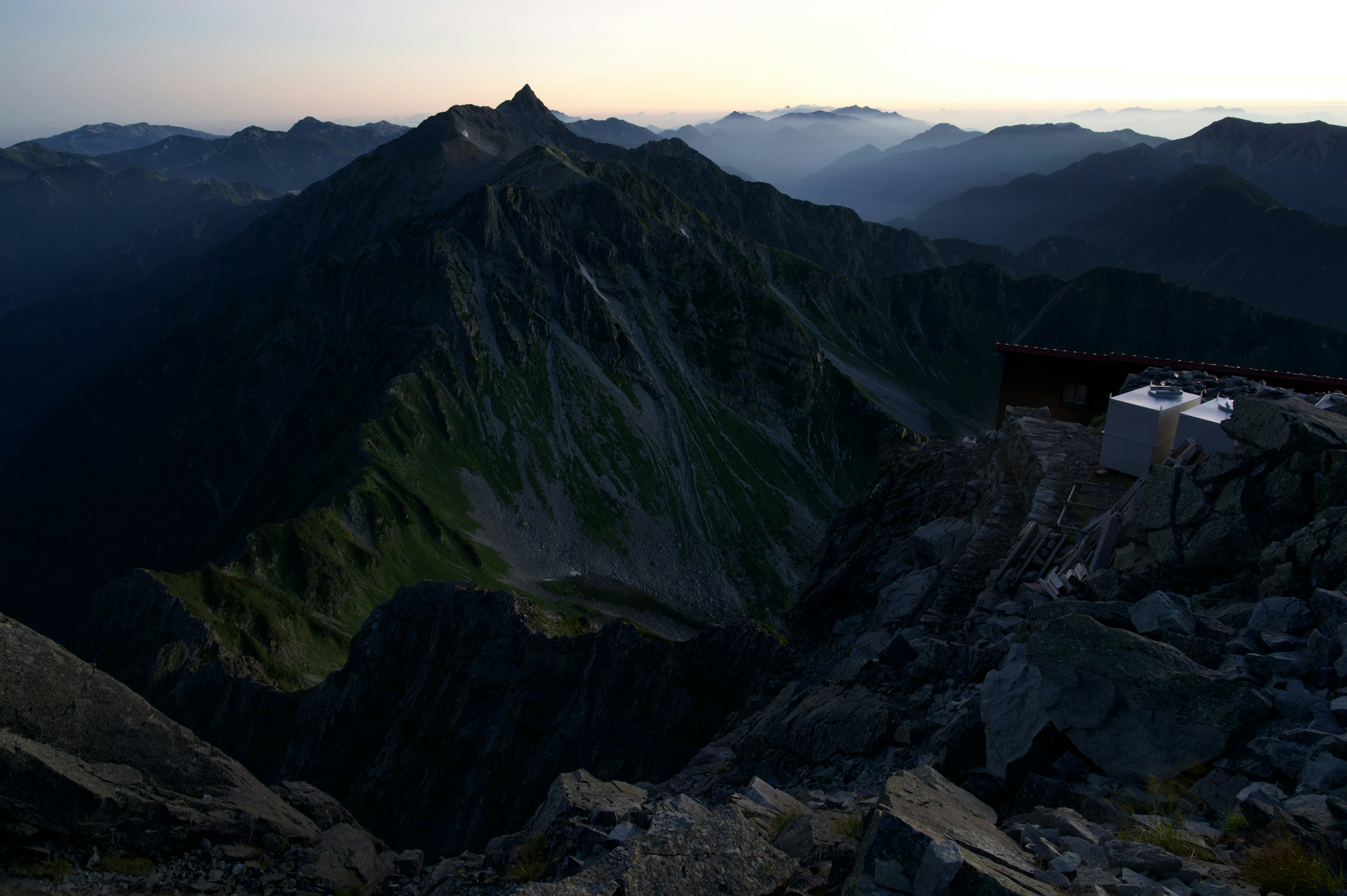 Paesaggio montano drammatico al crepuscolo con pendii verdi e terreno roccioso