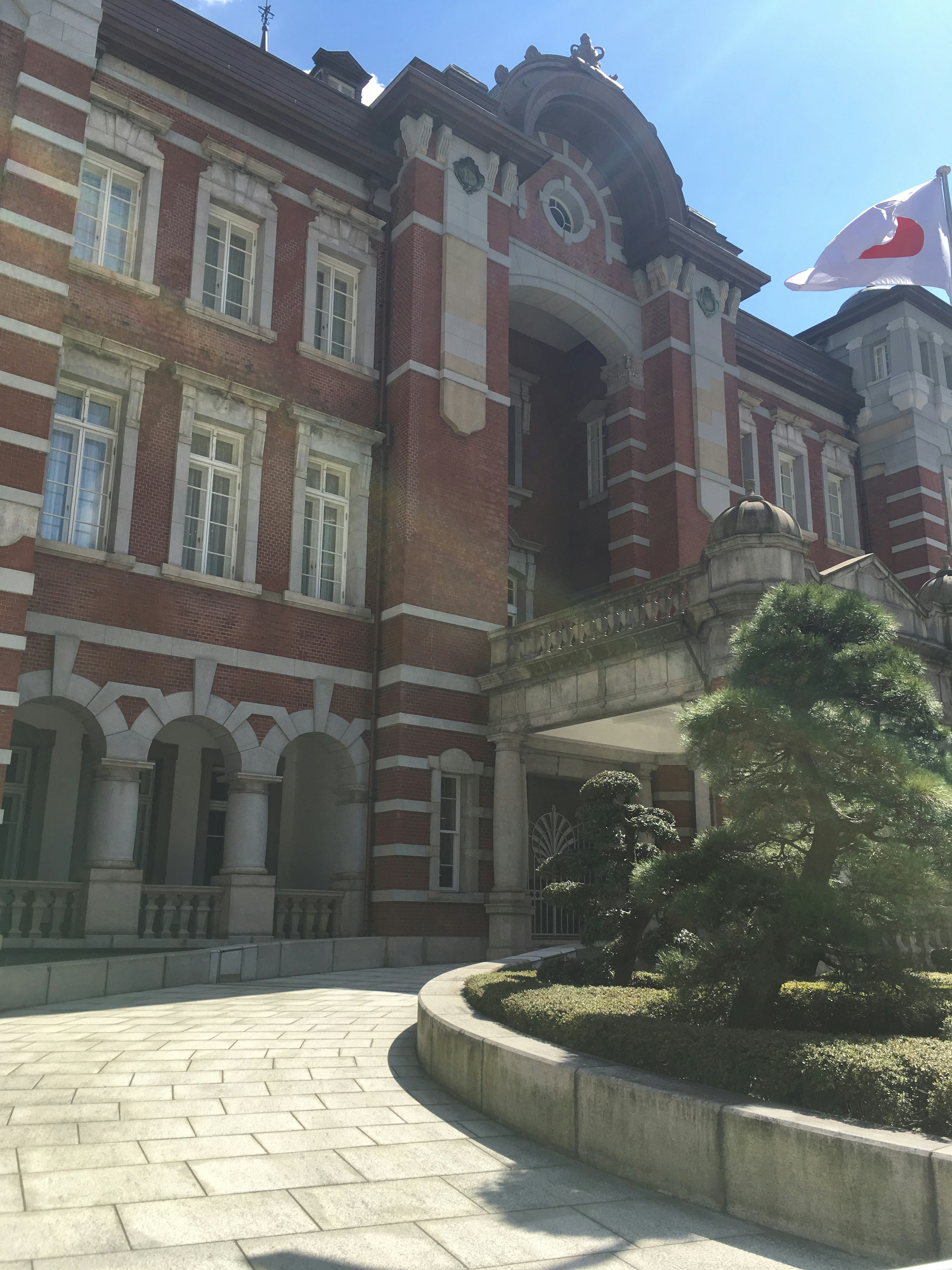 Stazione di Tokyo con architettura in mattoni rossi e bandiera giapponese