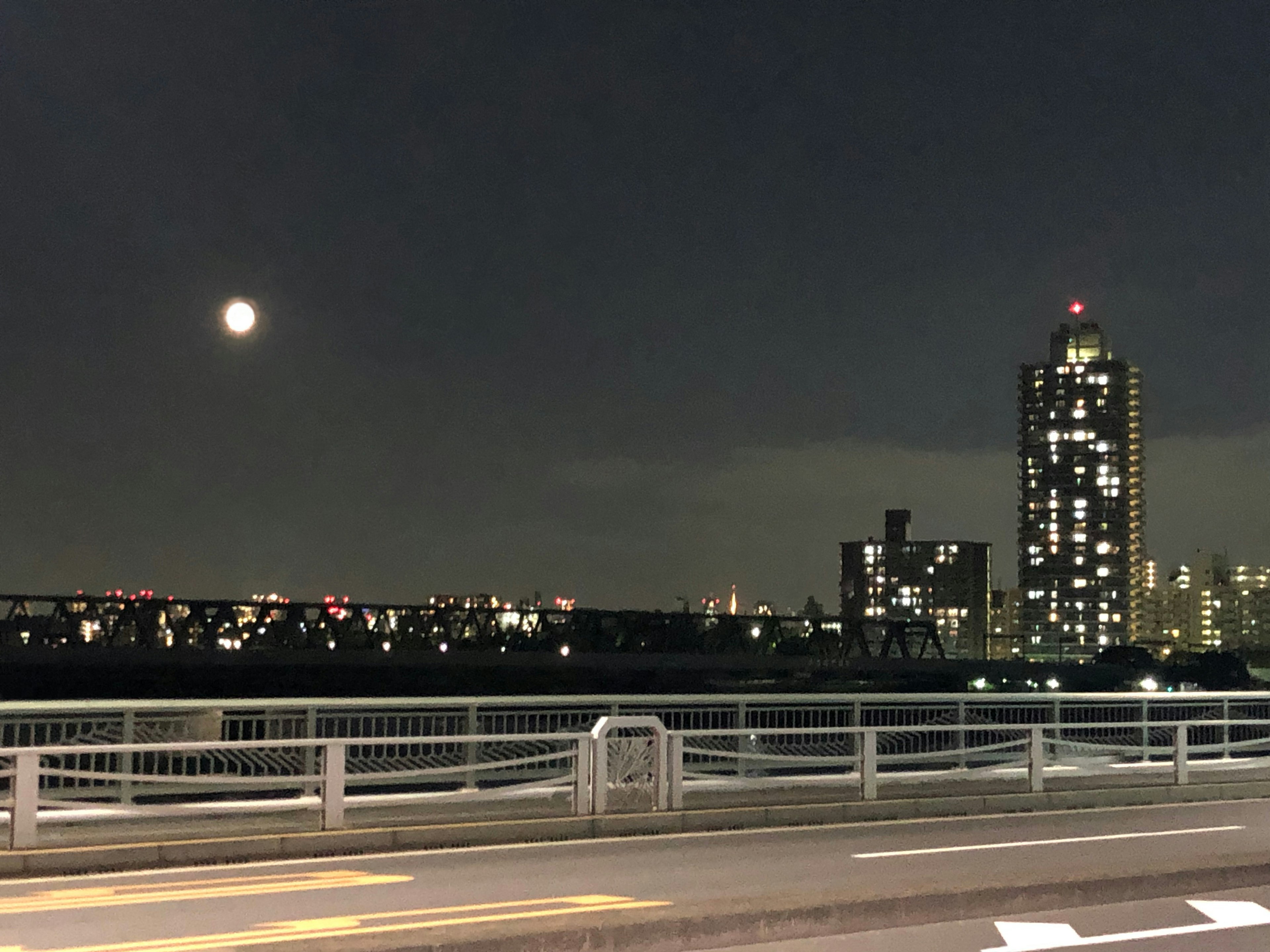 Vue nocturne avec une pleine lune et des gratte-ciel illuminés