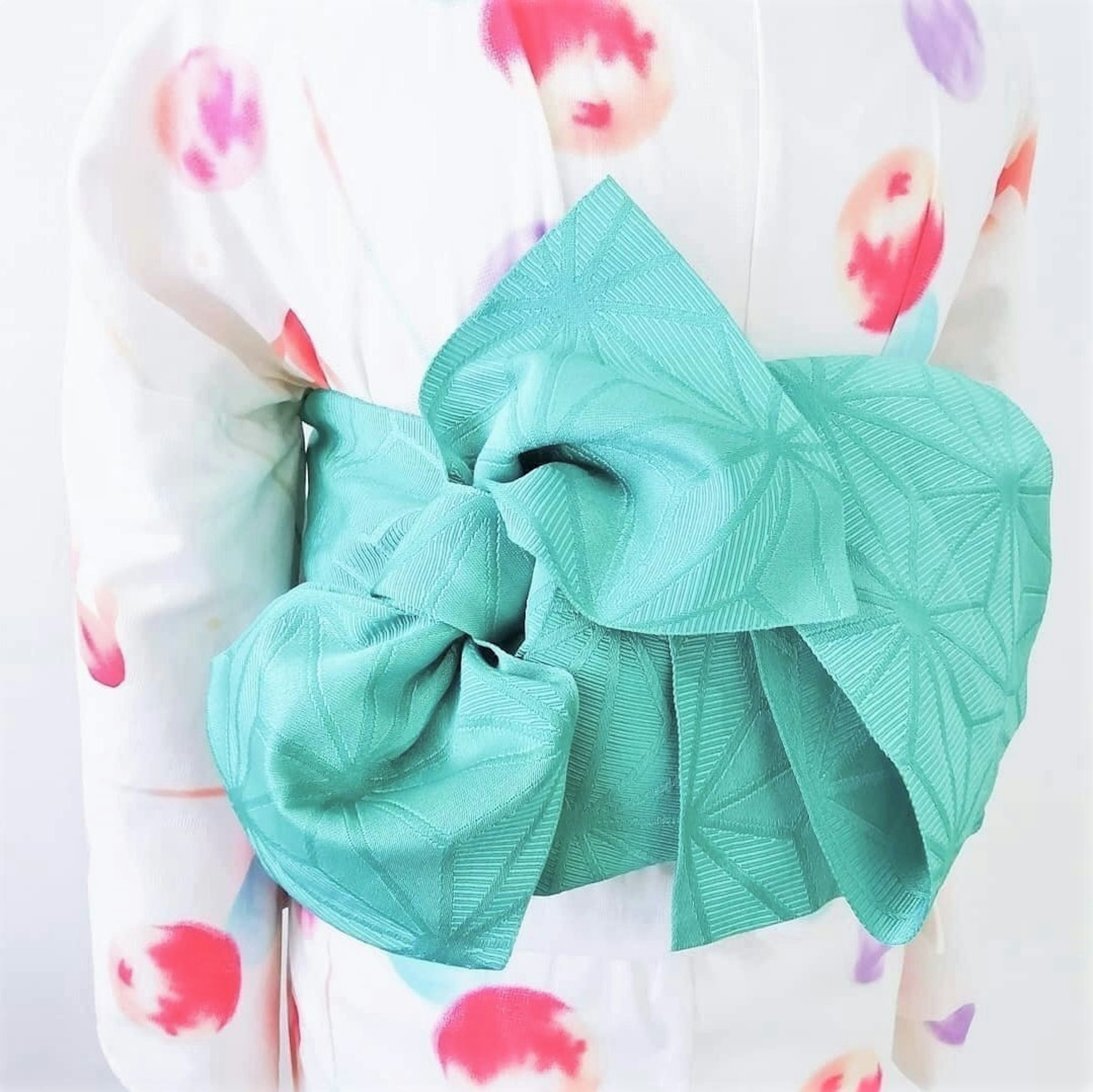 Un kimono à motifs floraux colorés avec un obi turquoise brillant noué élégamment dans le dos