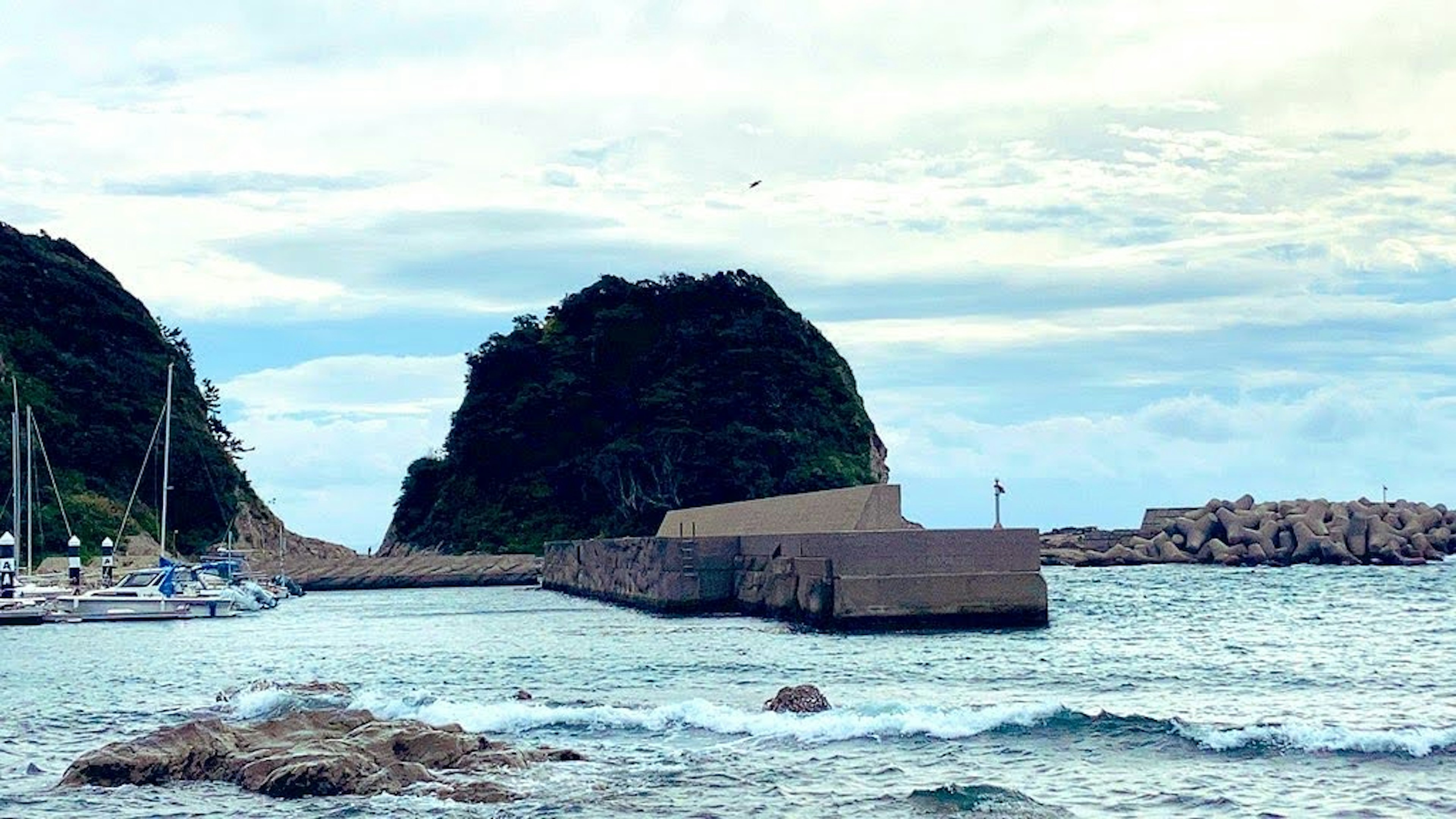 Küstenansicht mit Felsen und einem Hafen mit festgemachten Booten