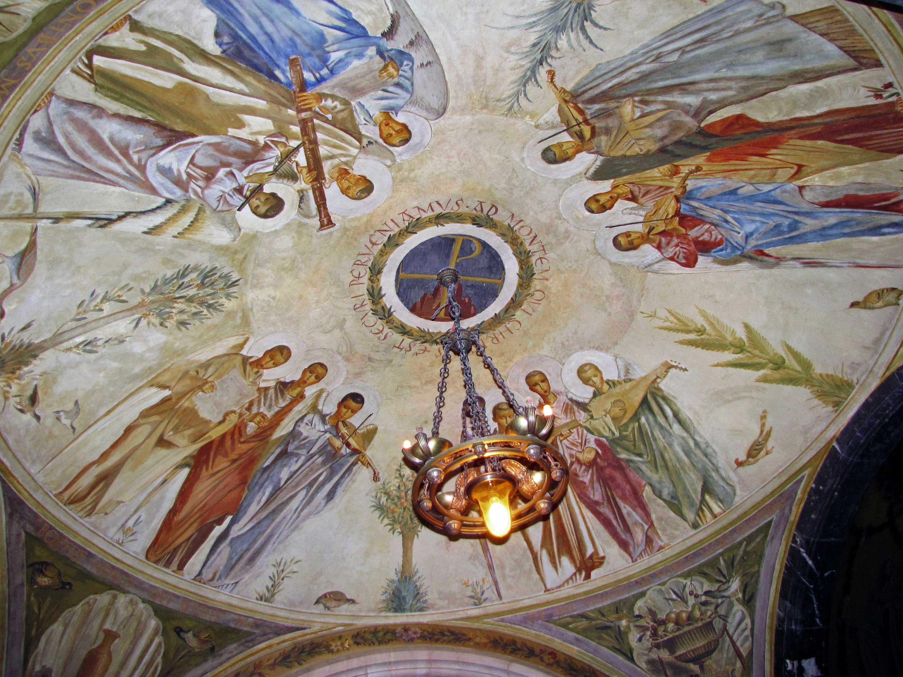 Interior of a church featuring a beautiful ceiling fresco depicting saints and angels in a circular arrangement