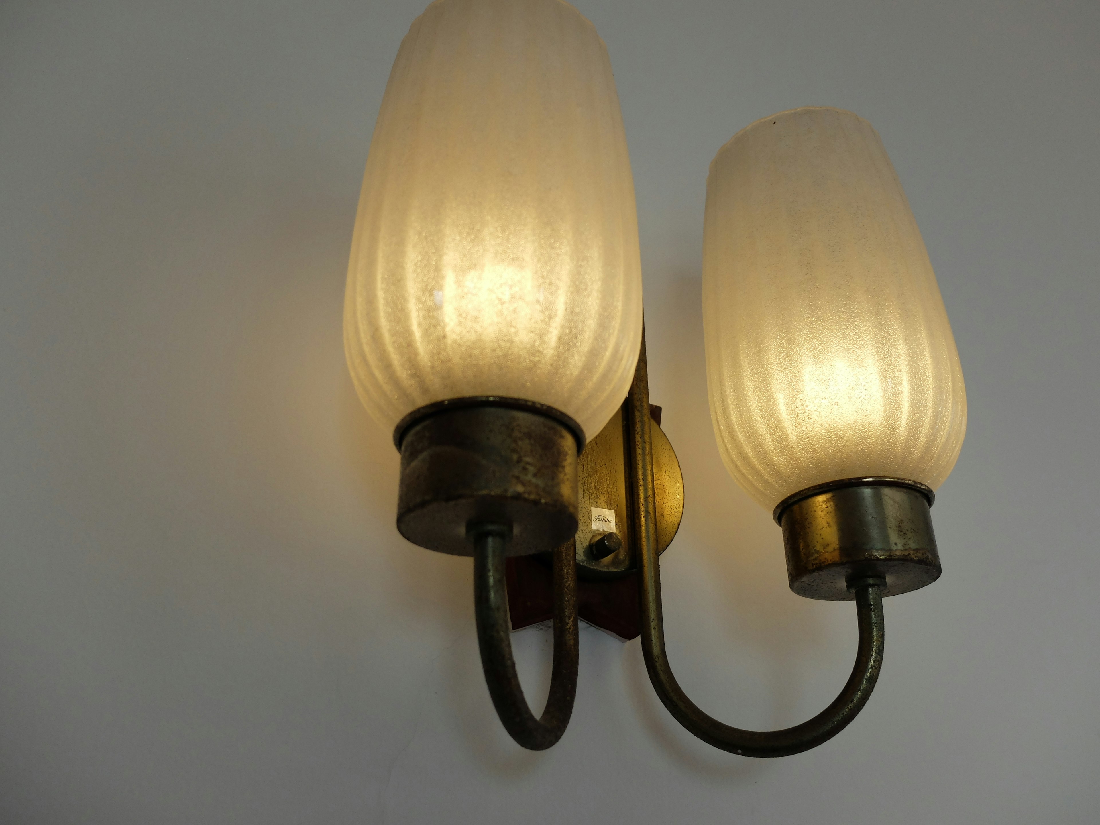 Wall-mounted light fixture with two lamps emitting warm light featuring a simple design