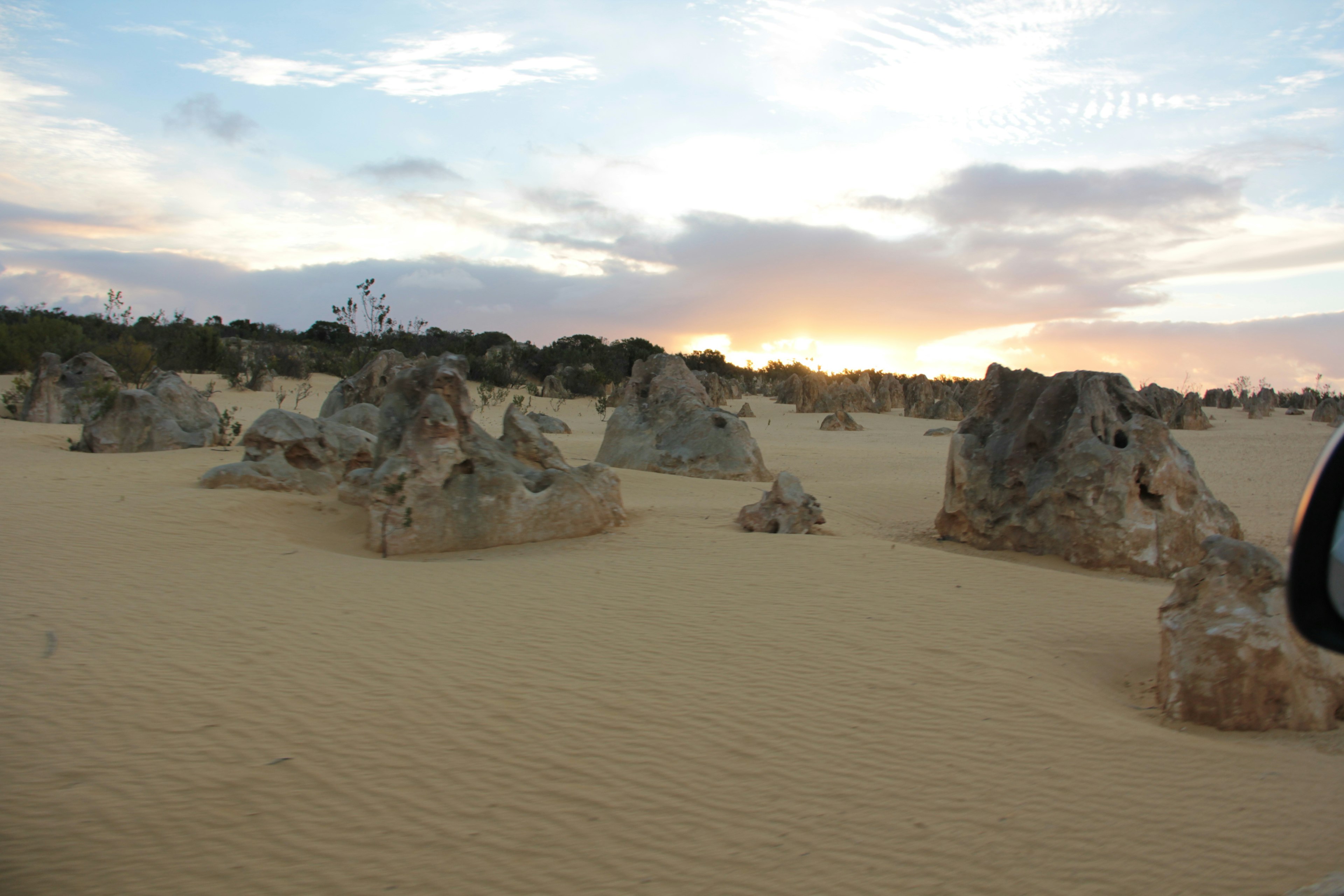 Vista escénica de formaciones rocosas en un paisaje arenoso al atardecer