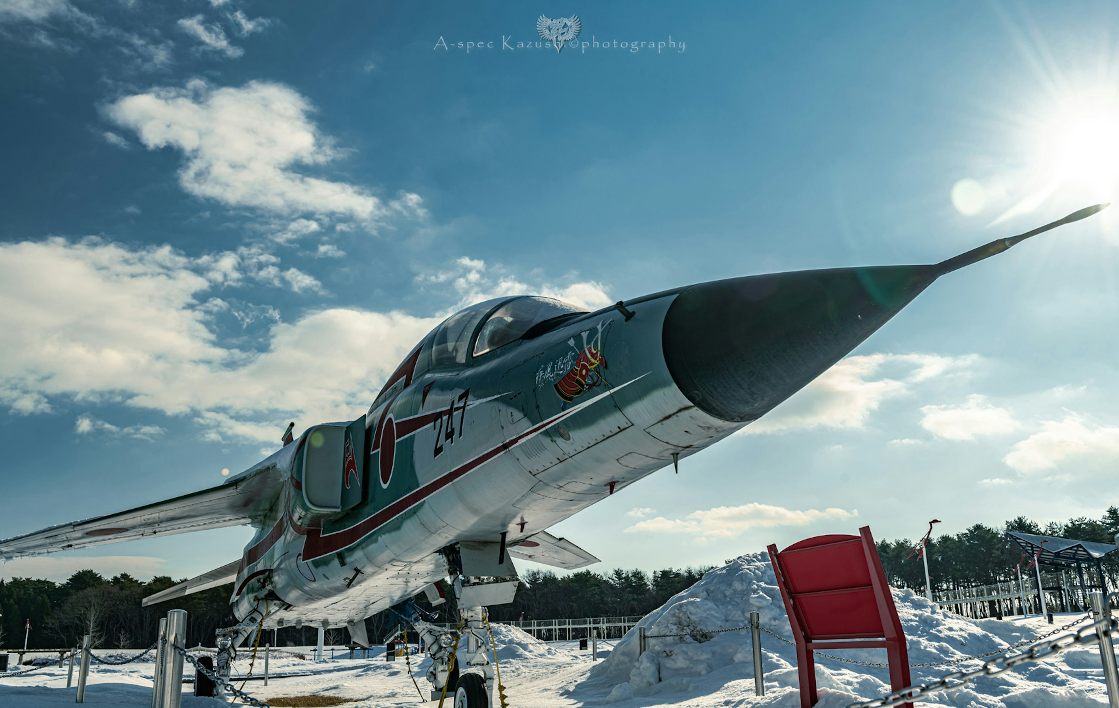 Side view of a fighter jet on snow with a blue sky