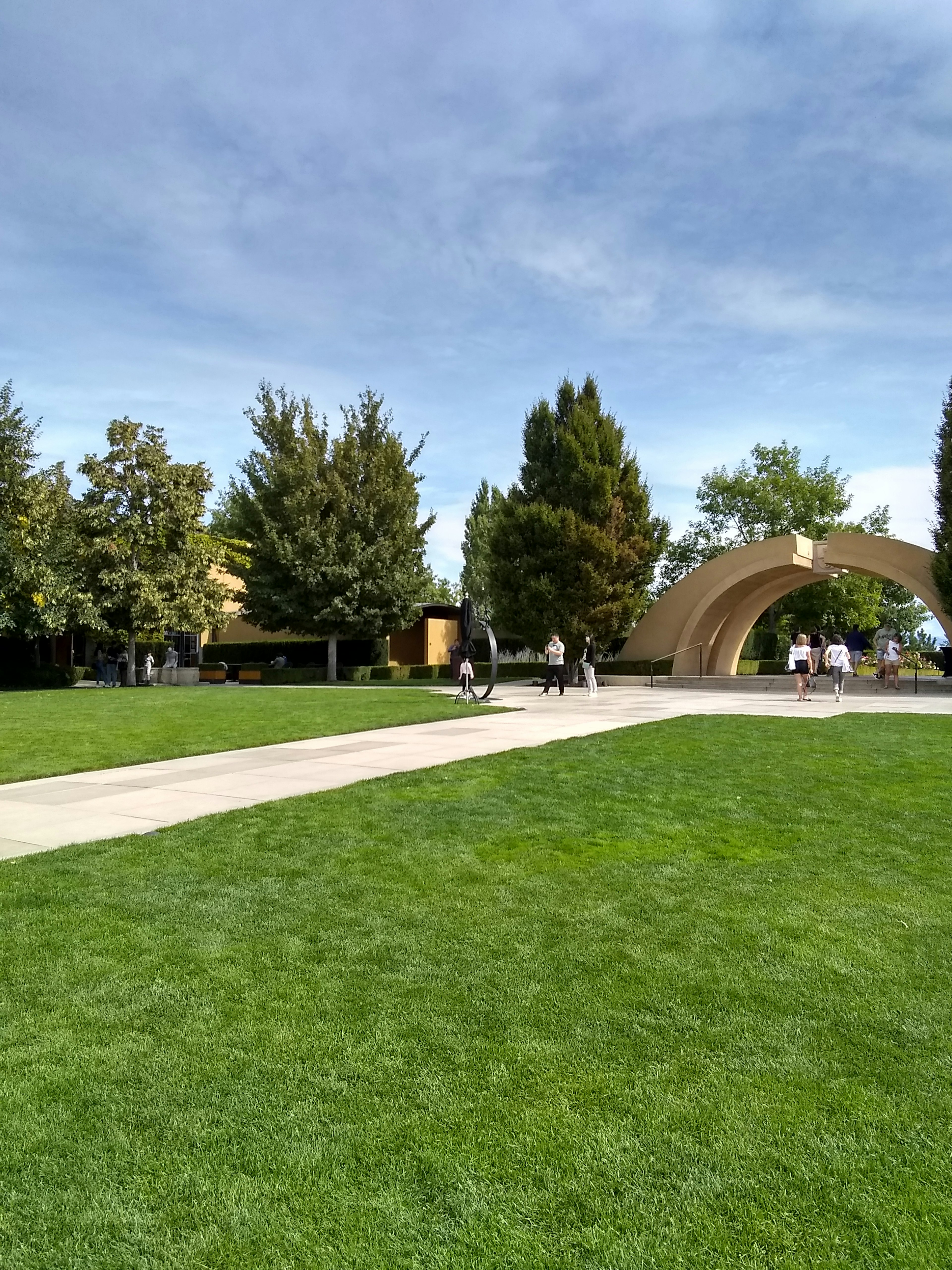 Paesaggio del parco con erba verde e alberi con un sentiero e una struttura ad arco