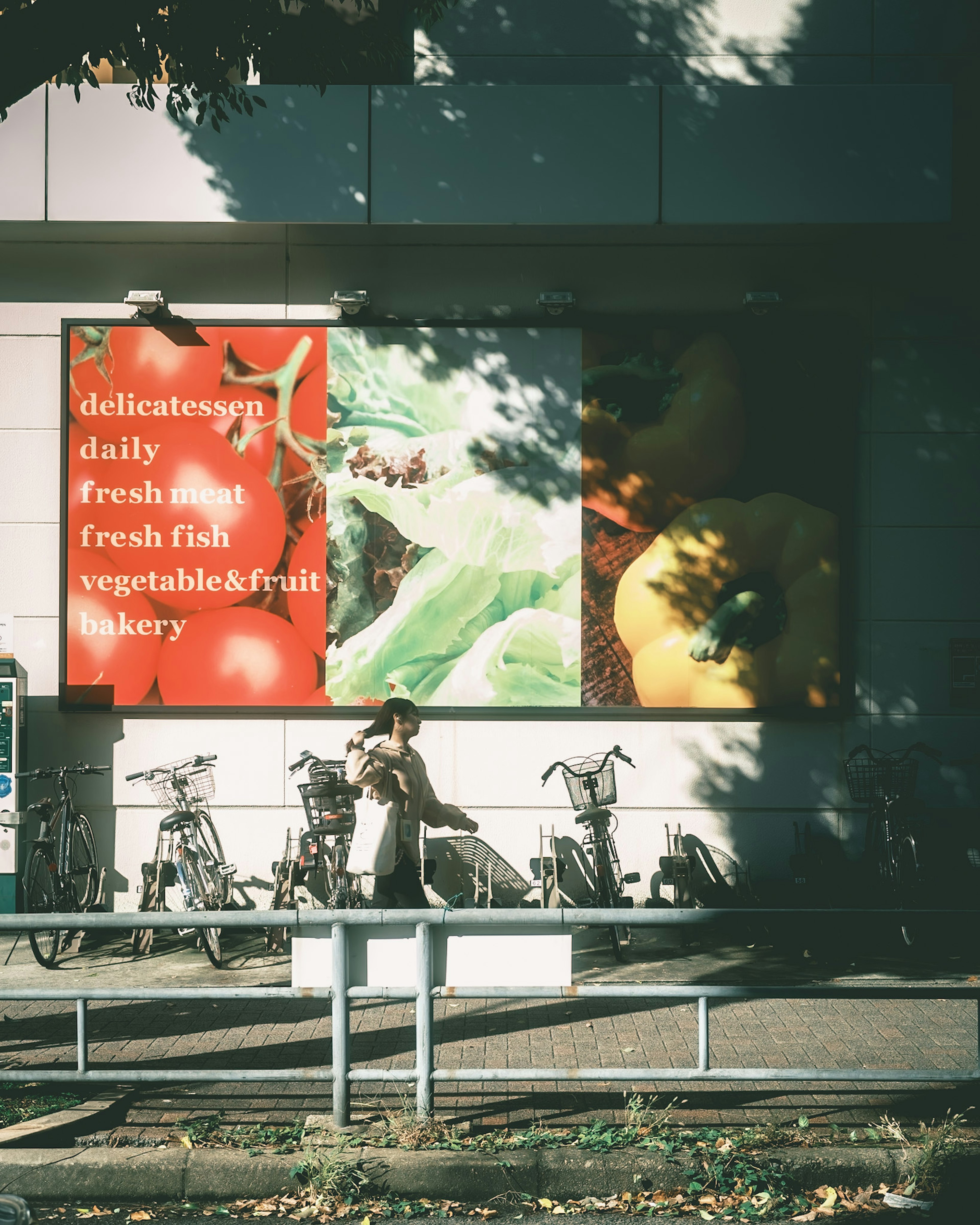 Exterior of a store featuring a fresh produce advertisement with bicycles parked nearby