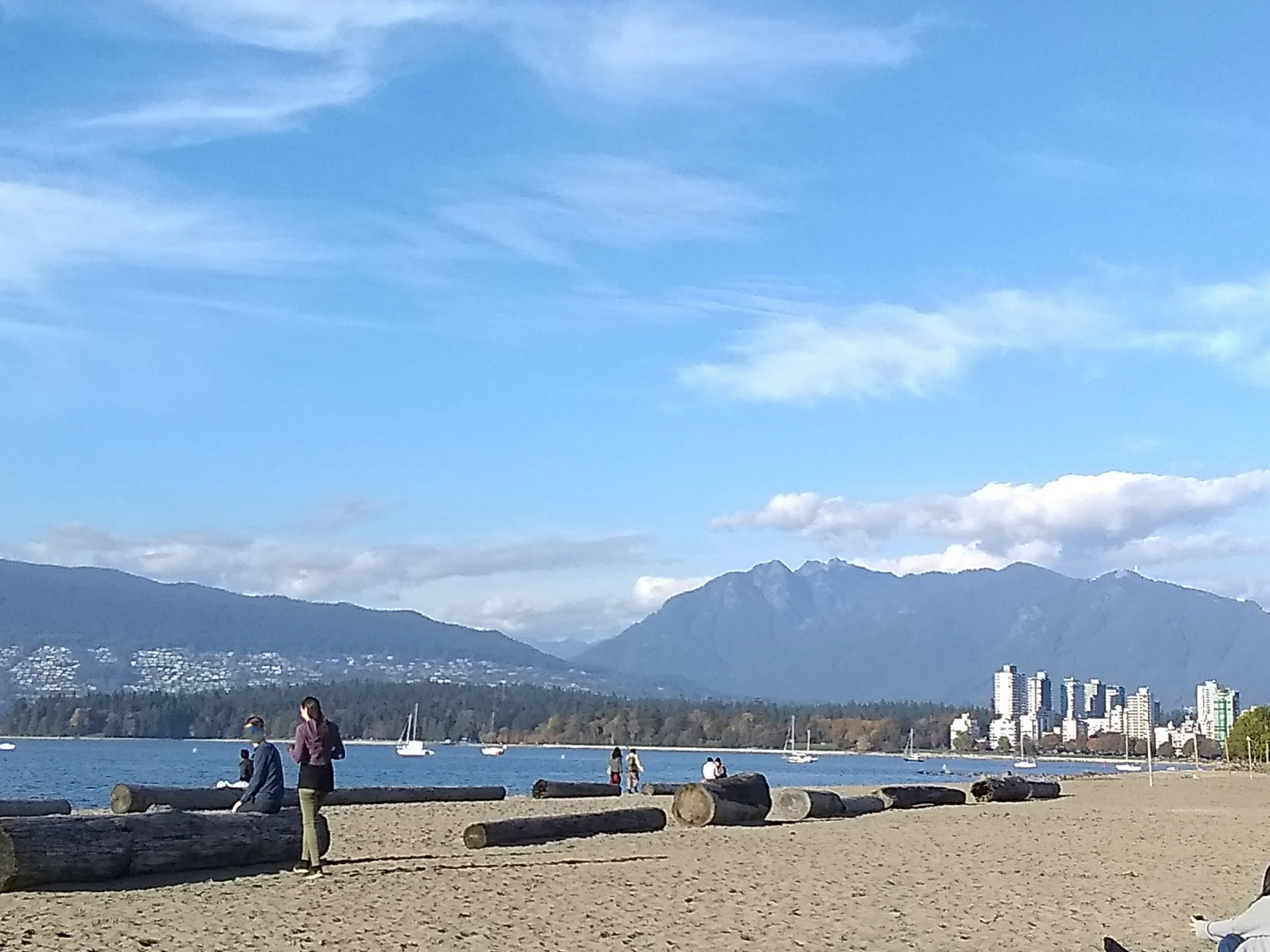 Strandszene mit Menschen, die sich entspannen blauer Himmel und Berge im Hintergrund