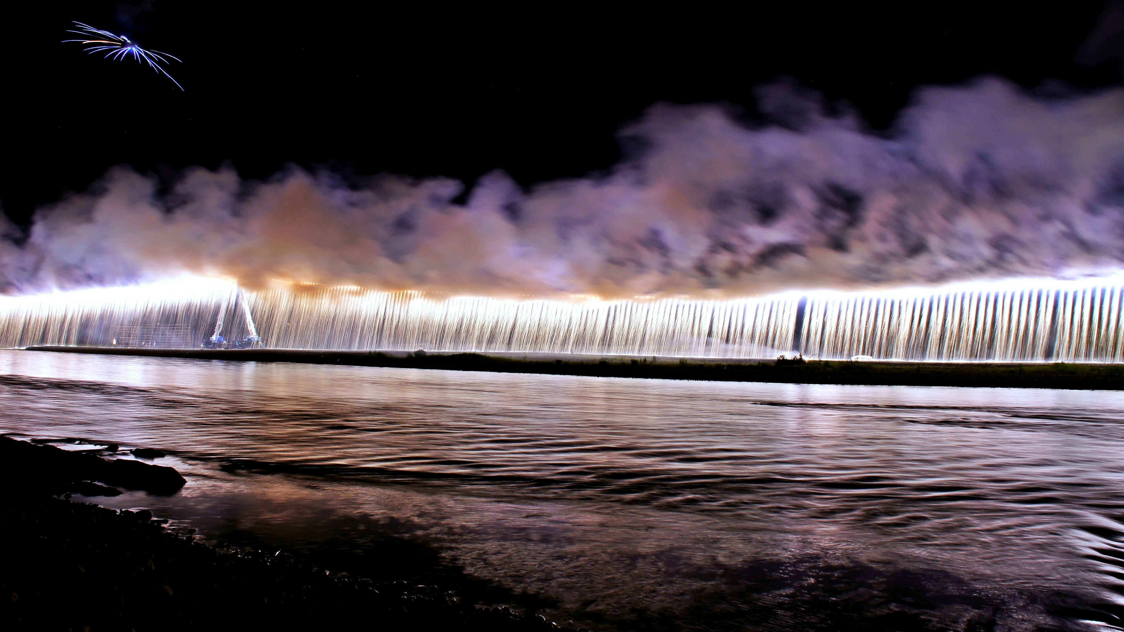 Rideau lumineux d'eau et de brume se reflétant sur l'eau nocturne