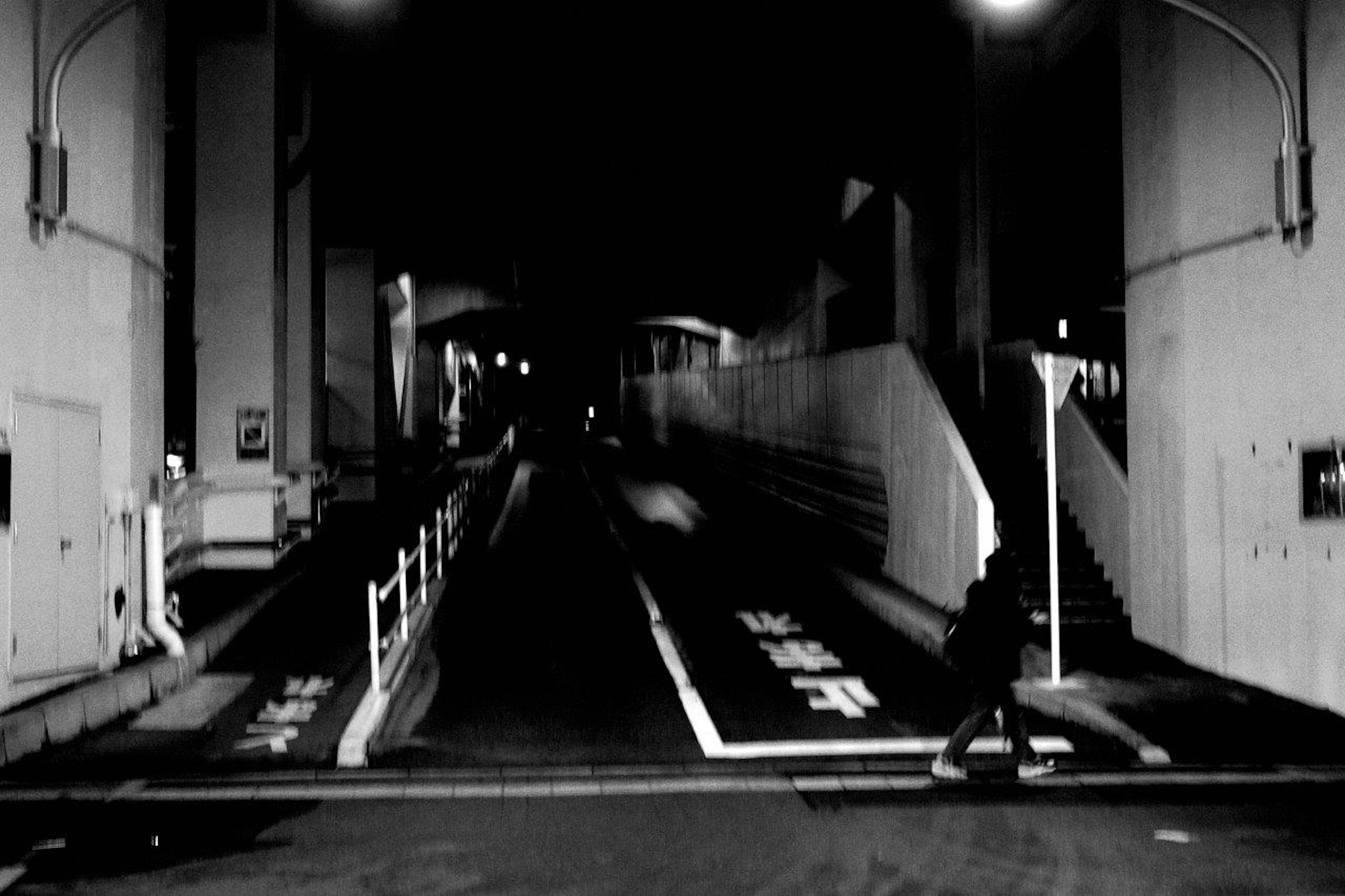 A person walking under a dark tunnel with visible stairs