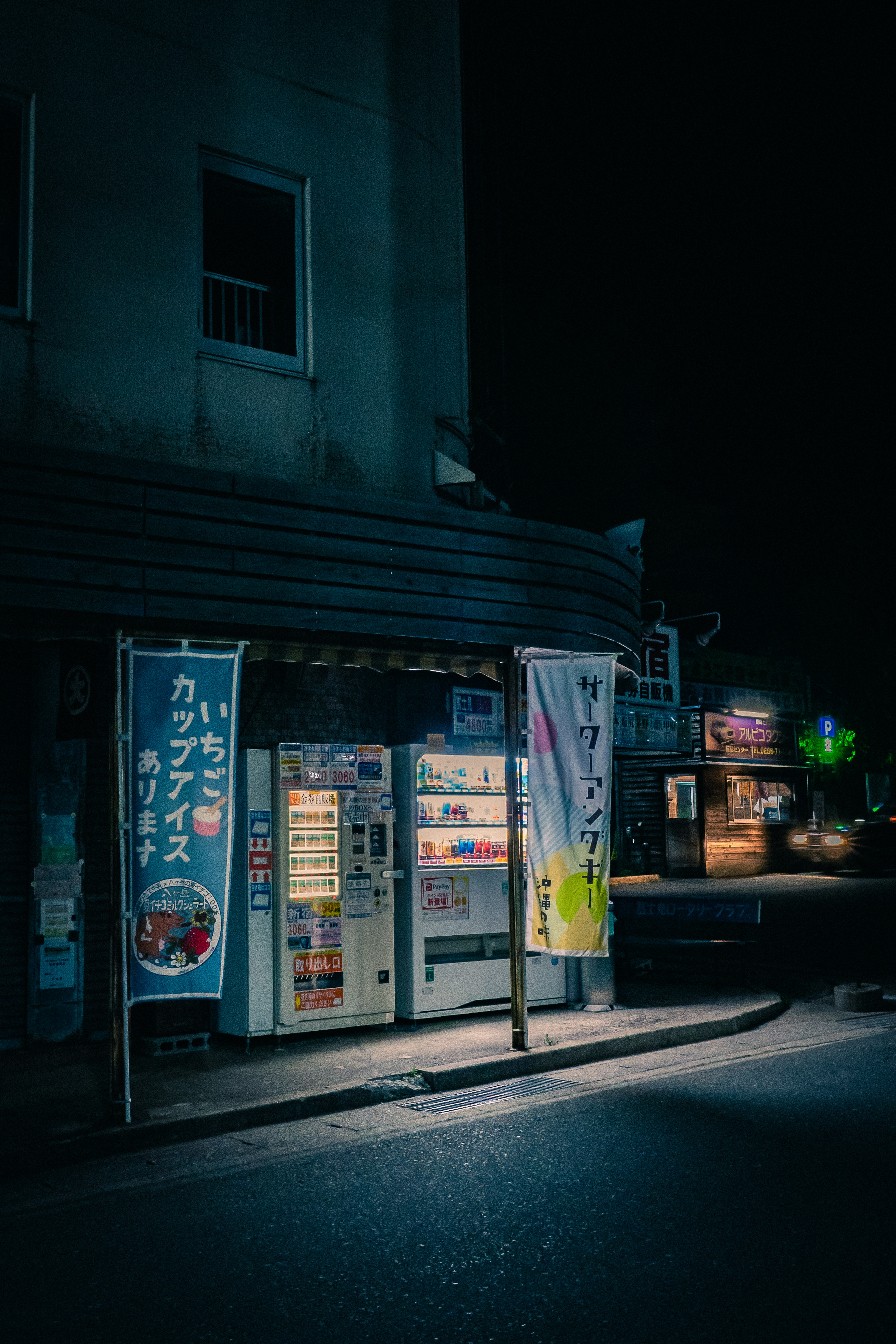 Distributore automatico e insegne all'angolo di una strada di notte