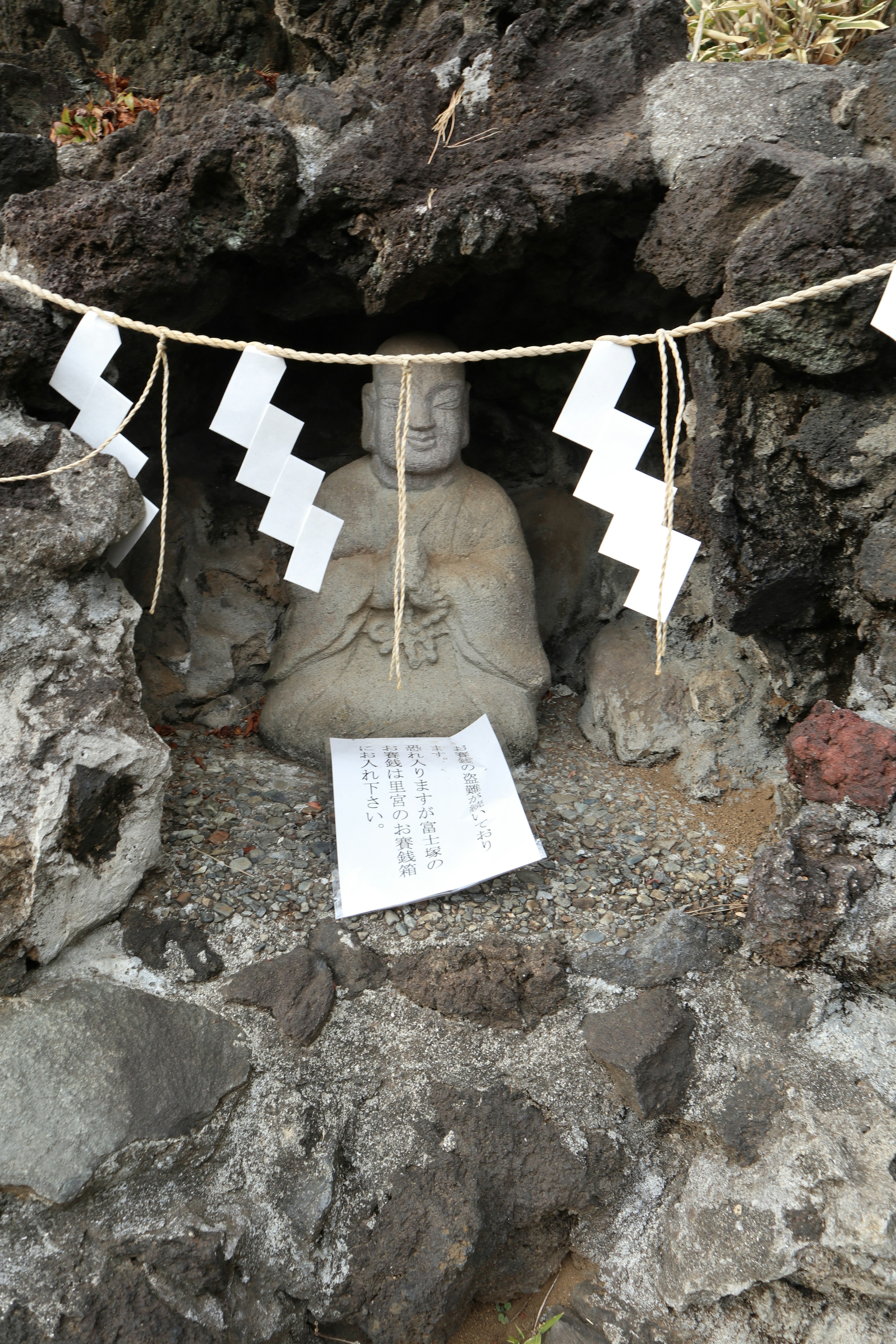 Statue de Bouddha en pierre assise dans une grotte avec des décorations blanches