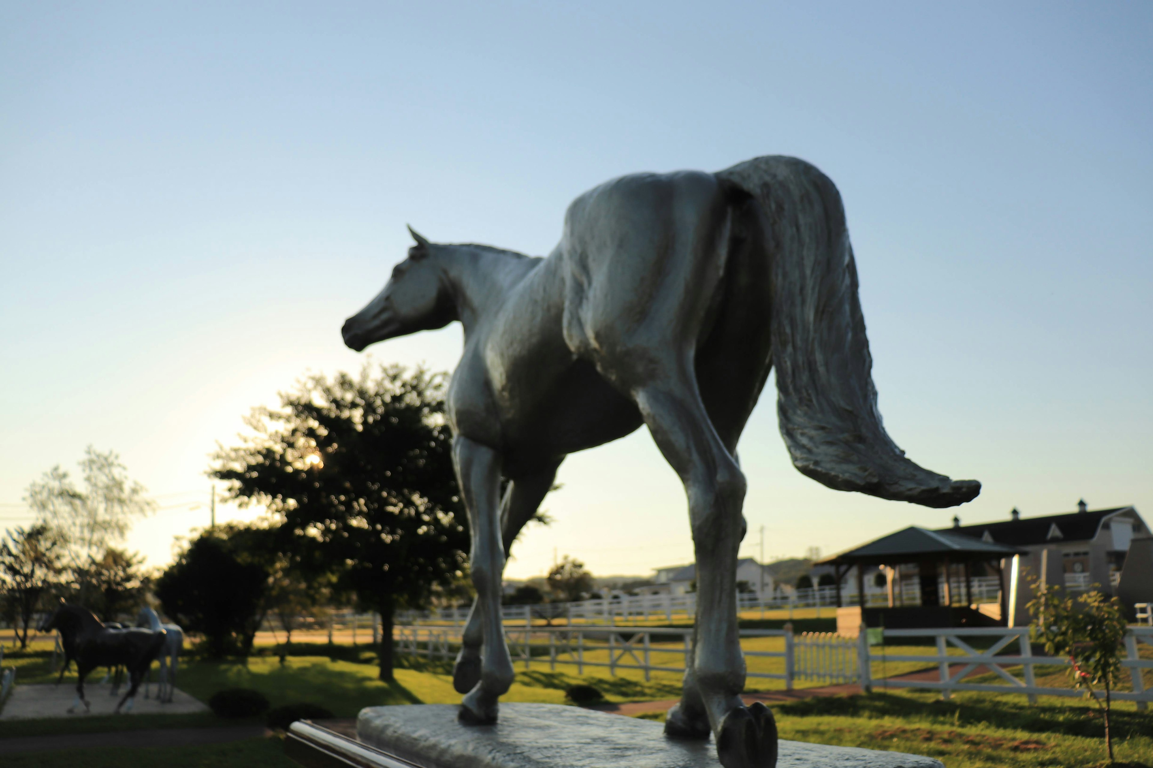 Una scultura di cavallo che si erge contro il tramonto in un ambiente rurale