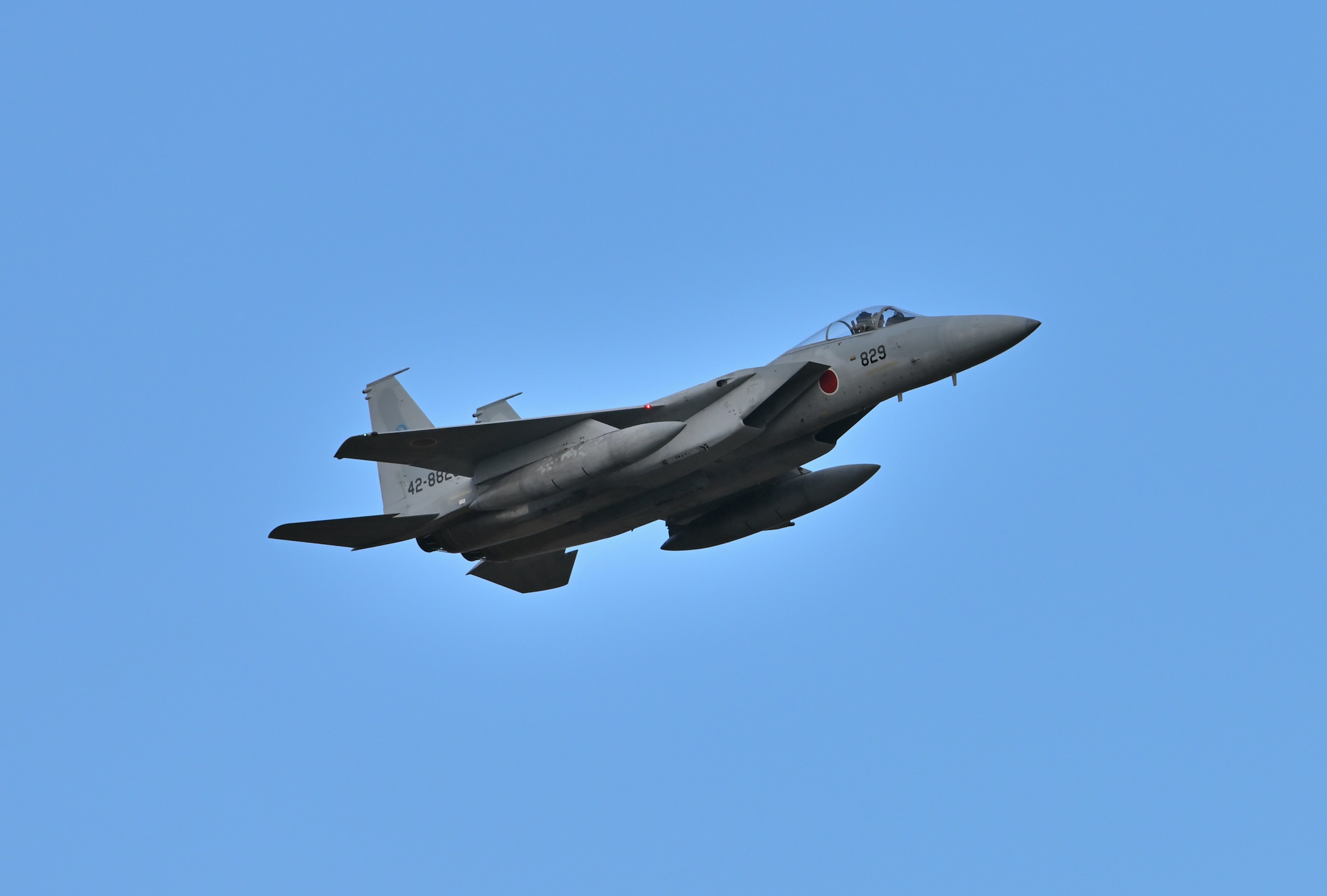 An F-15 fighter jet flying against a clear blue sky