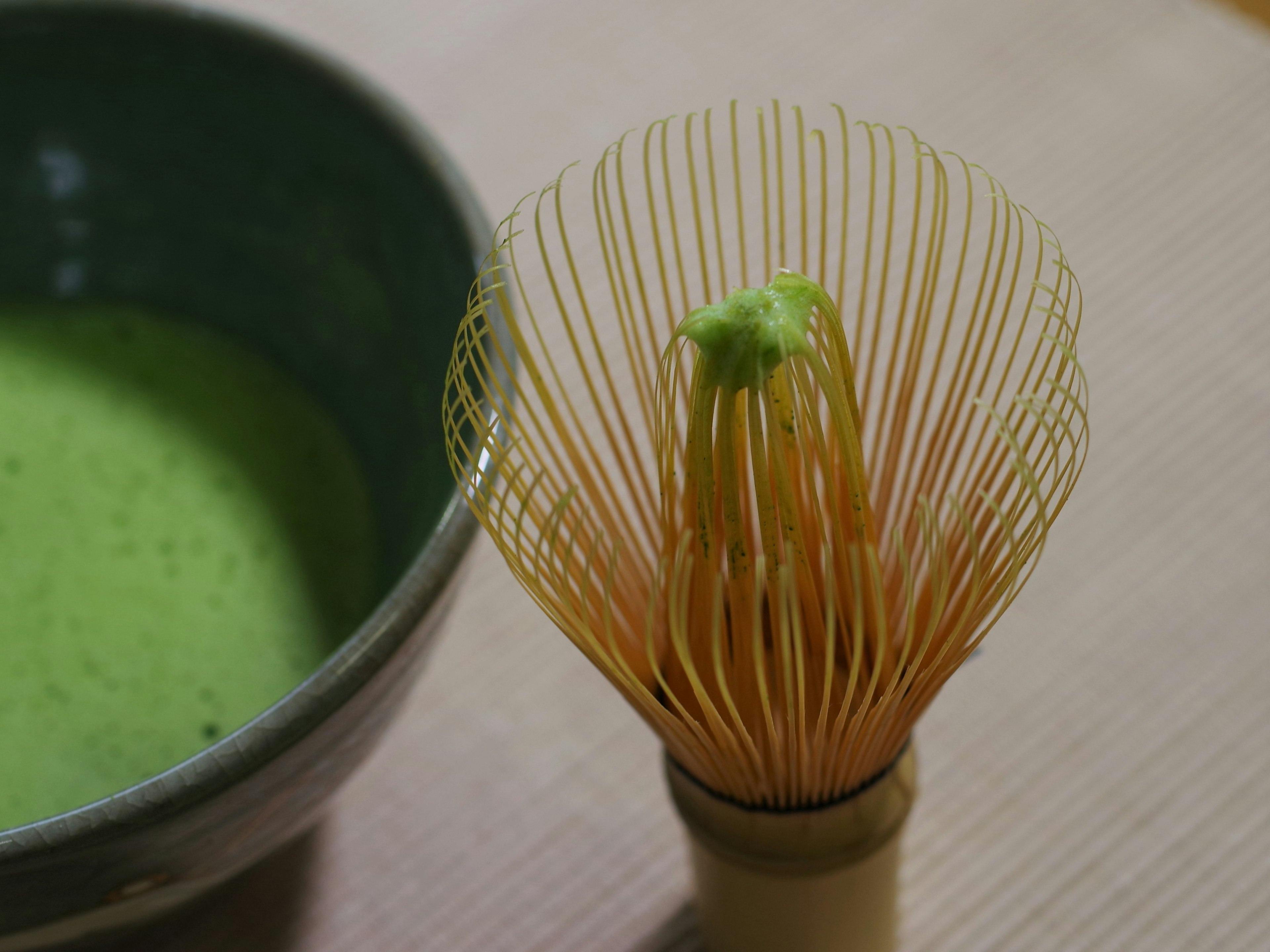 Close-up of a matcha bowl and a bamboo whisk