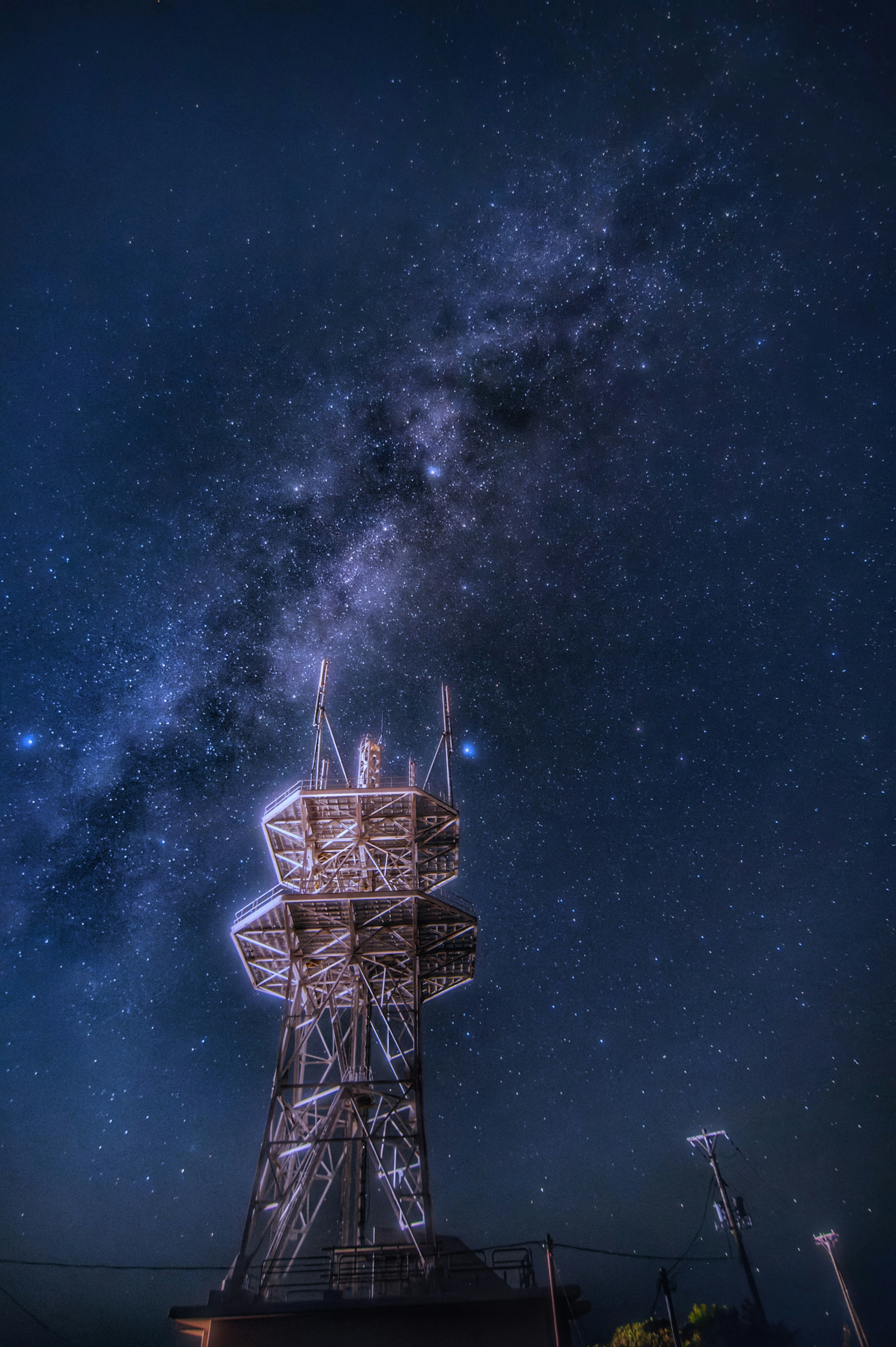 Beautiful view of the Milky Way shining in the night sky with a communication tower