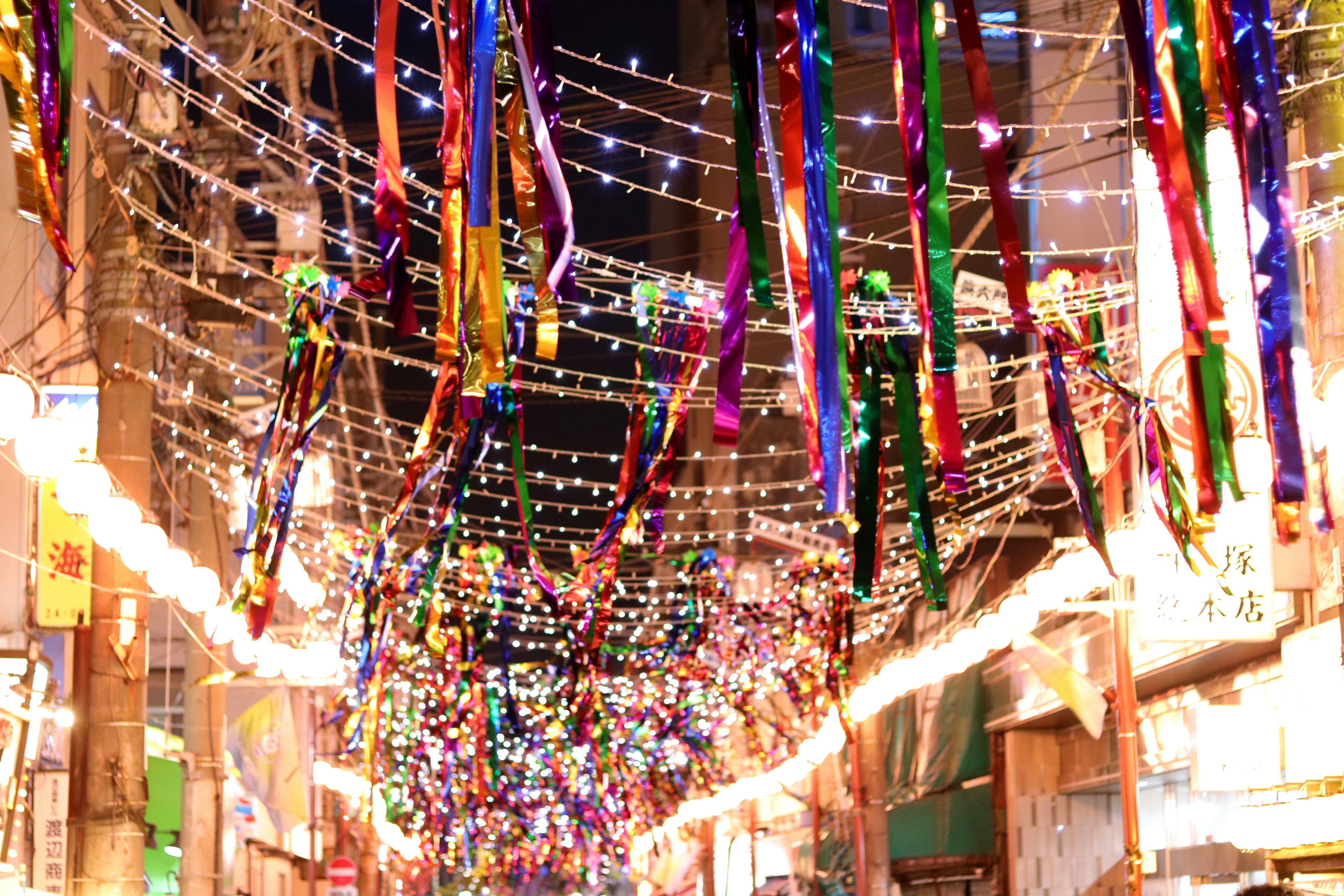 Cintas coloridas y luces colgando en una calle decorada durante un festival nocturno