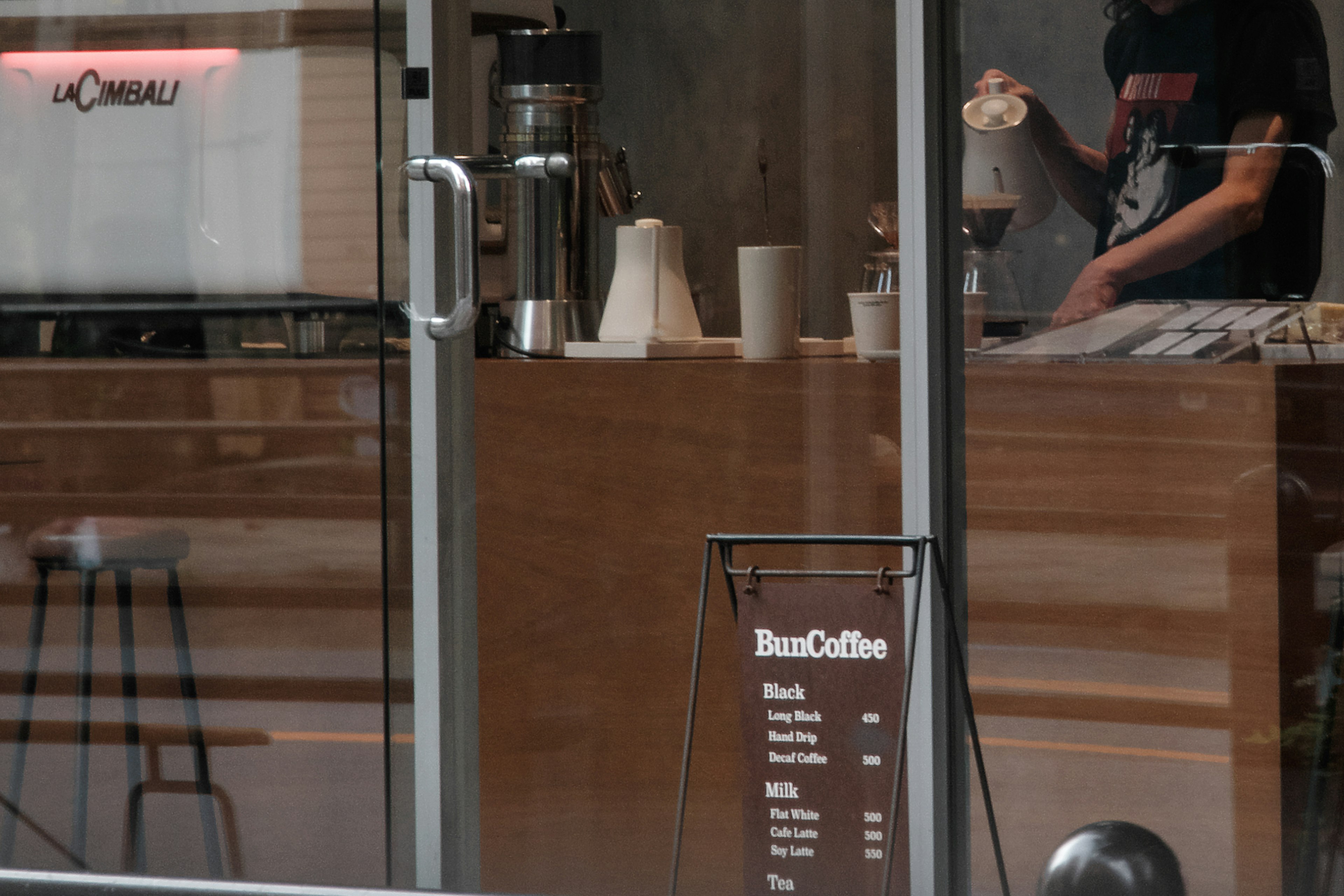 Barista preparando café visible a través de la ventana de la cafetería