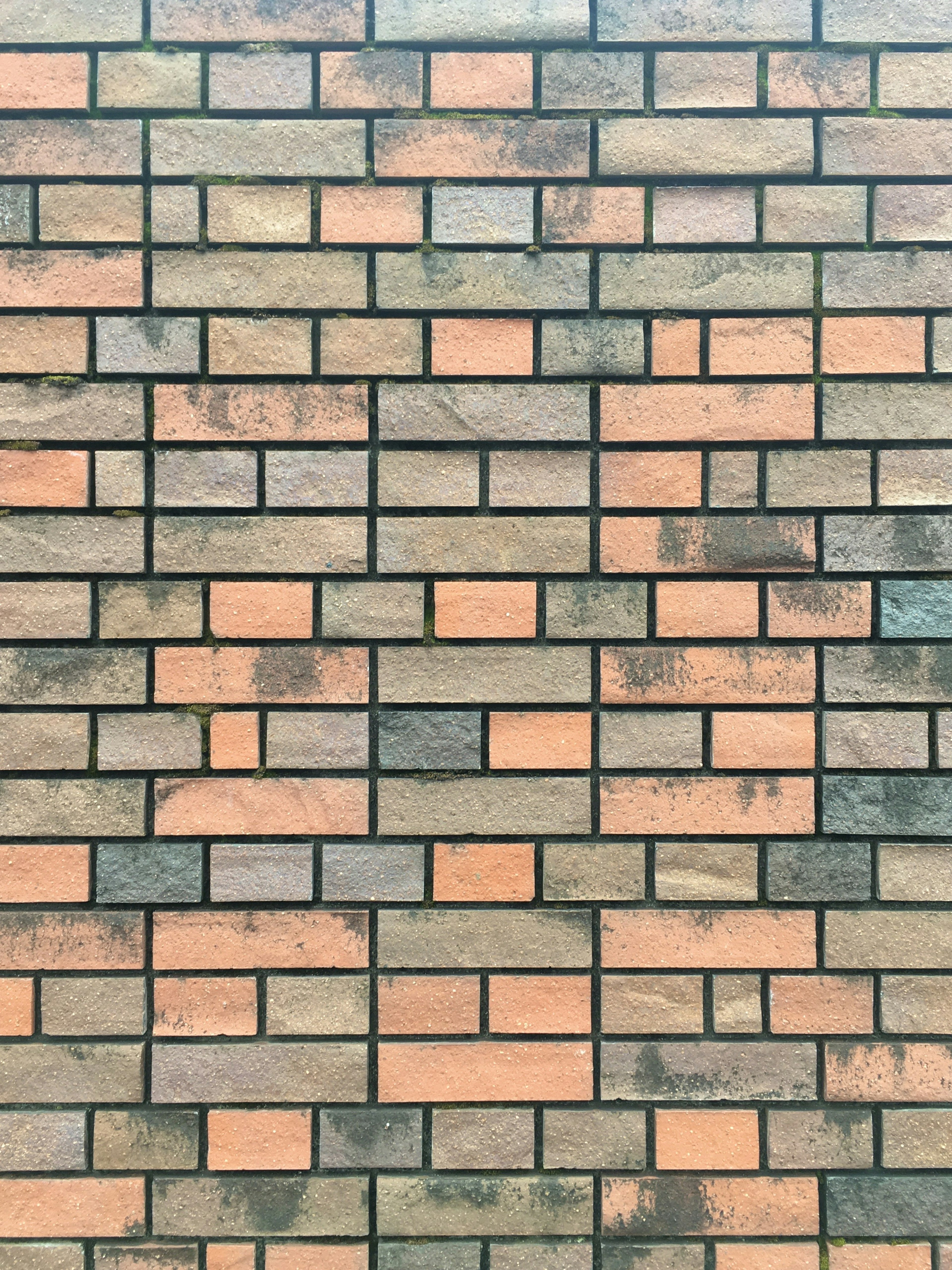 Pattern of alternating reddish-brown and black bricks on a wall